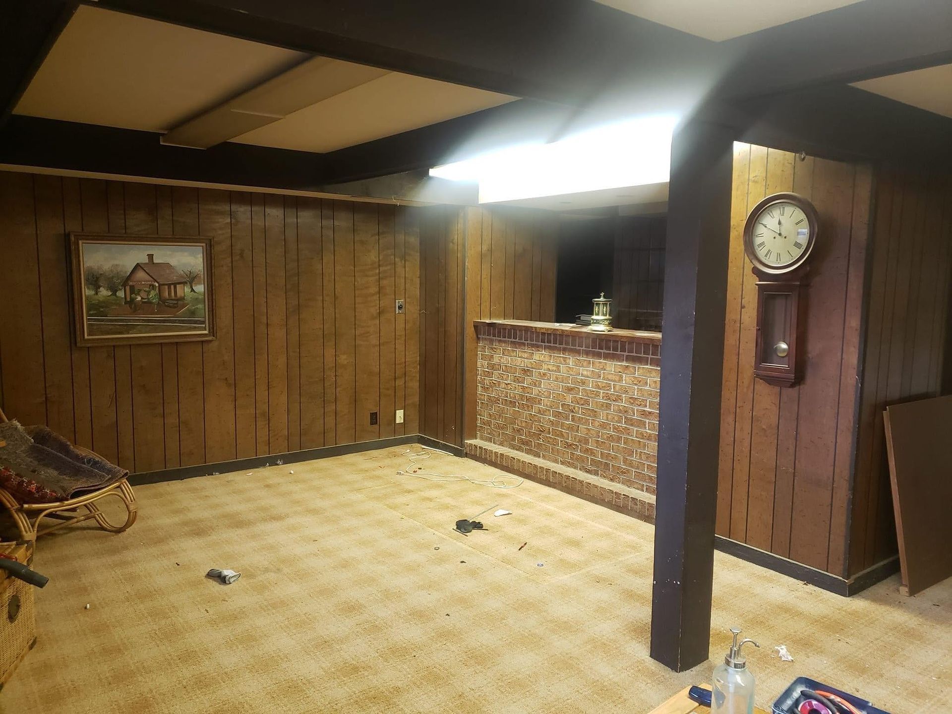 A living room with wood paneling and a clock on the wall.