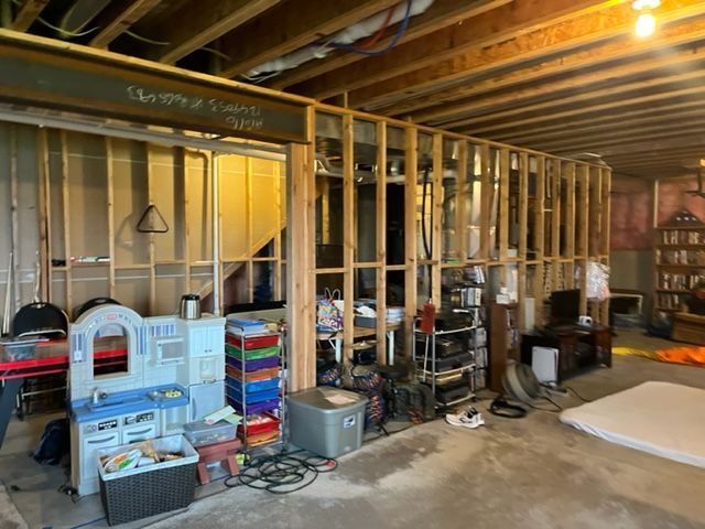 A basement with a lot of stuff in it and a play kitchen.