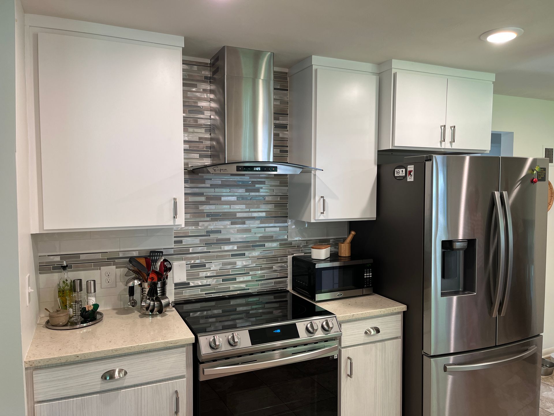 Kitchen with white cabinets, stainless steel appliances, and a tiled backsplash.