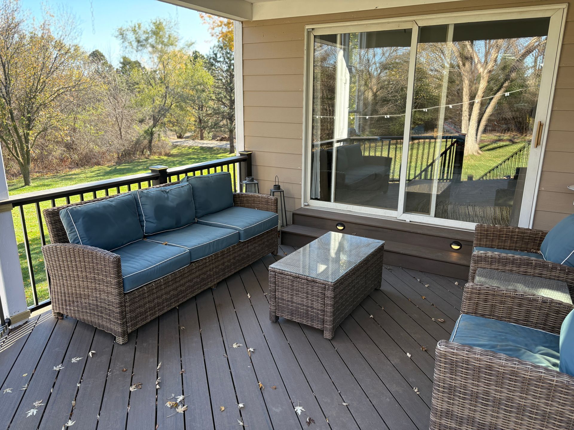 A patio with a couch , chairs , table and sliding glass doors.