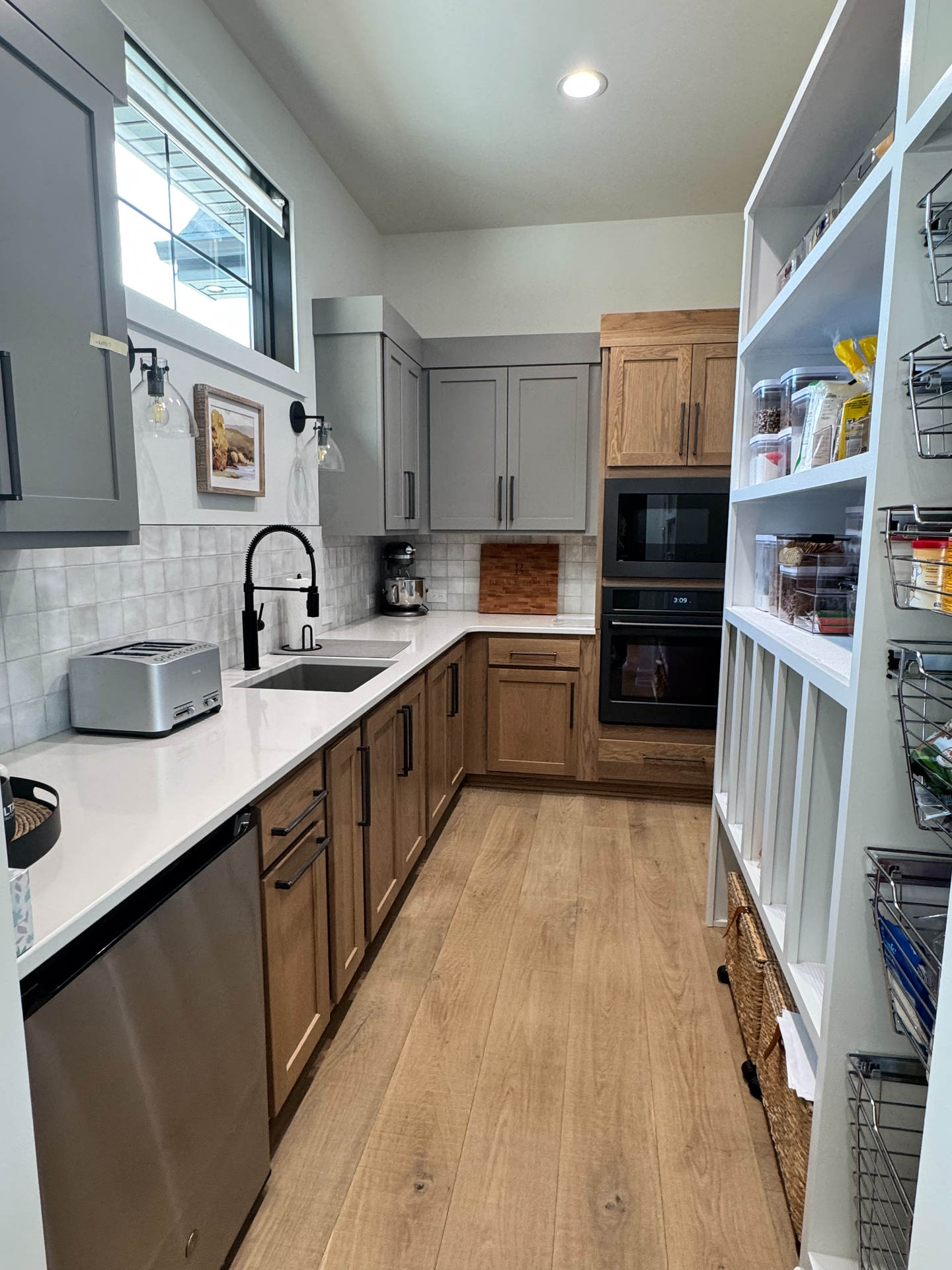 A kitchen with wooden cabinets , stainless steel appliances , a sink , and a pantry.