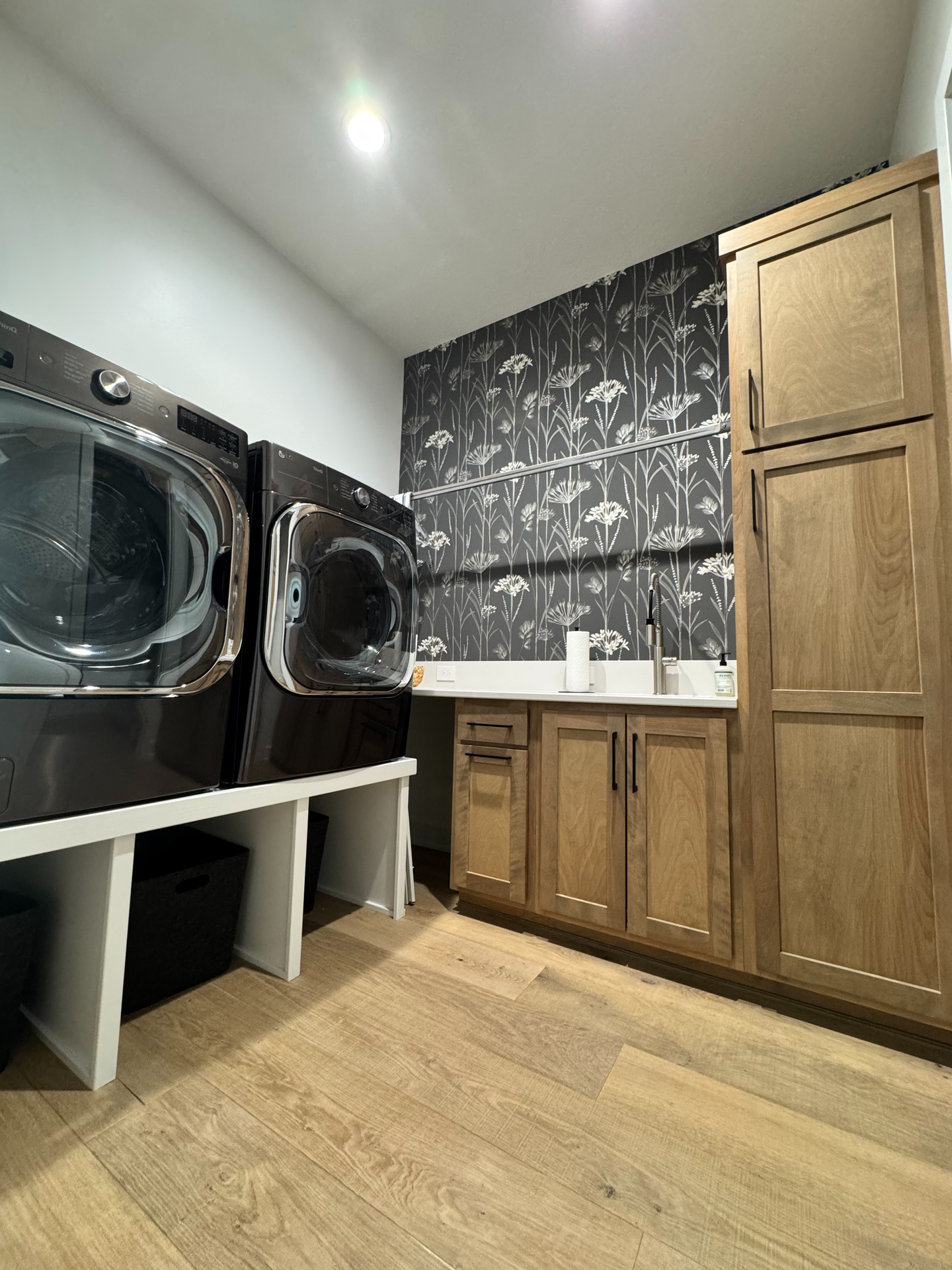 A laundry room with a washer and dryer and wooden cabinets.
