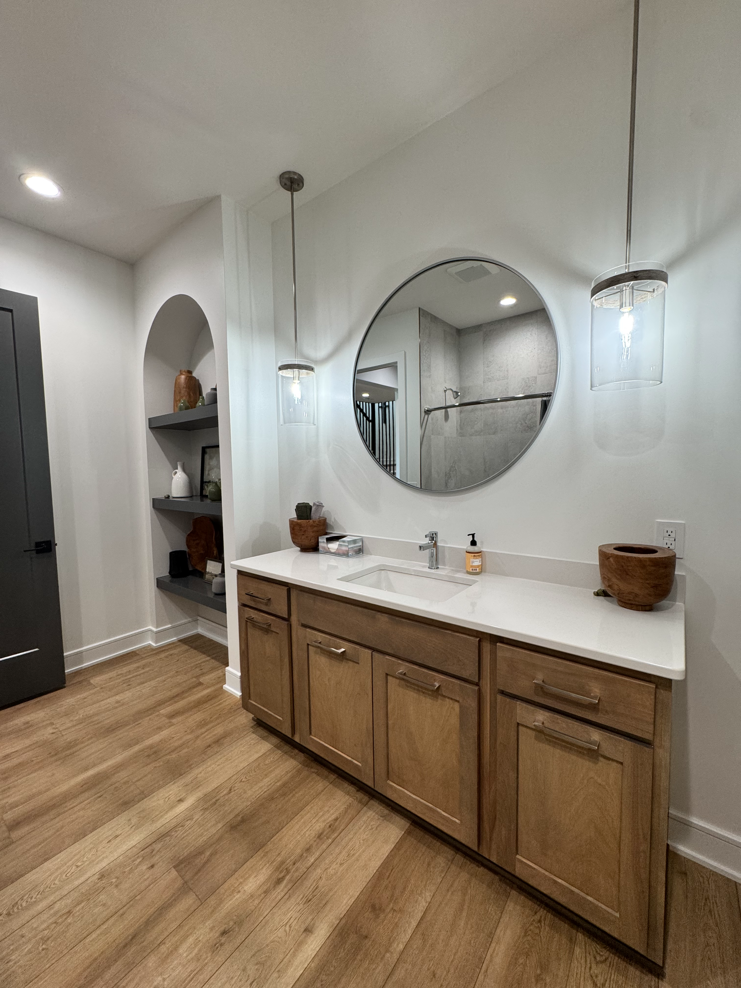 A bathroom with a sink , mirror and wooden cabinets.