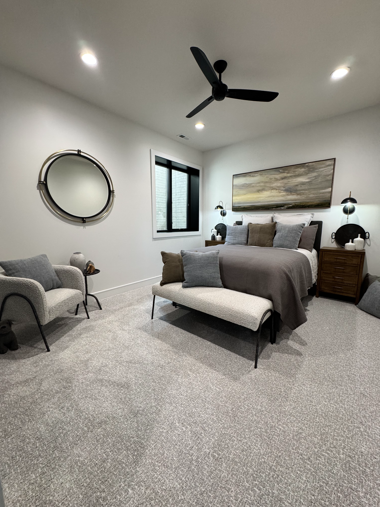 A bedroom with a bed , chair , mirror and ceiling fan.