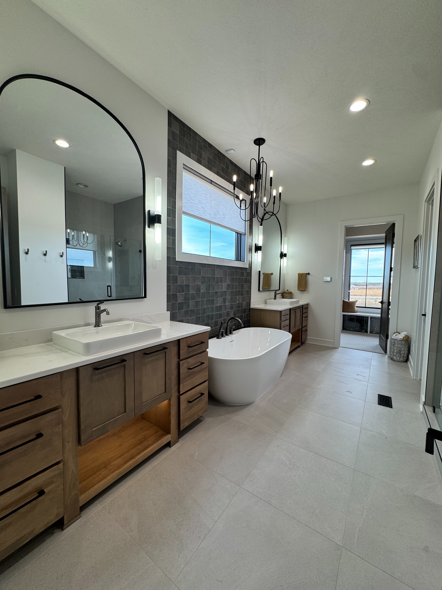 A bathroom with two sinks , a bathtub , and a large mirror.