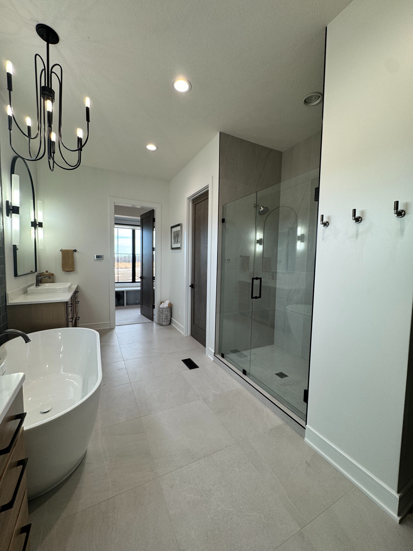 A bathroom with a tub , sink , shower and chandelier.
