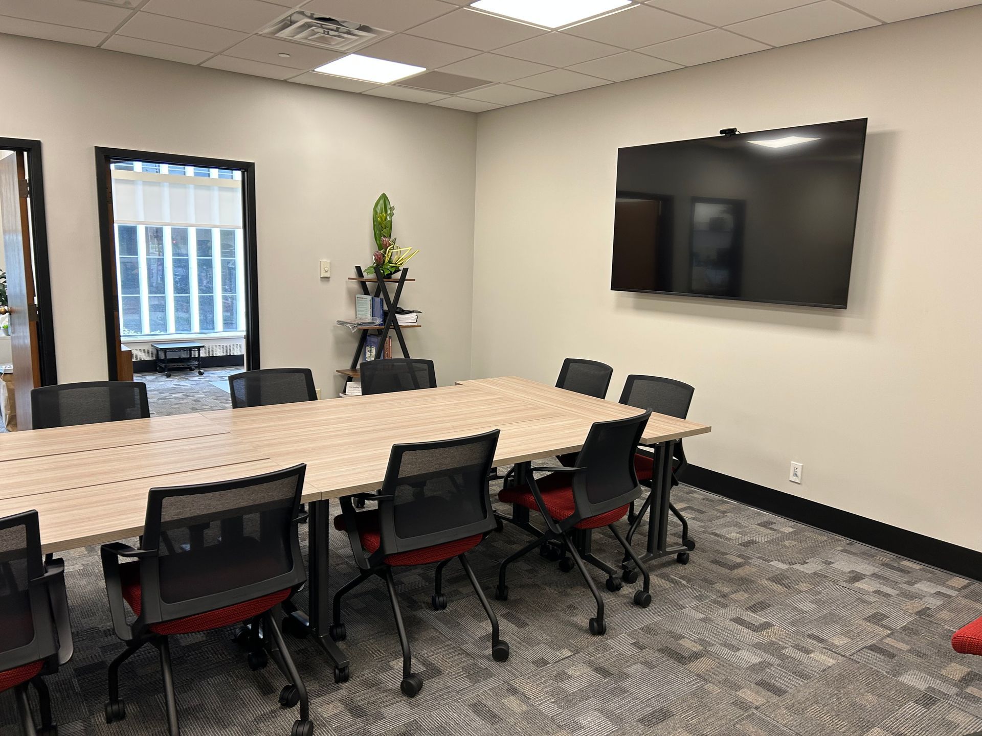 A conference room with a long table and chairs and a flat screen tv.