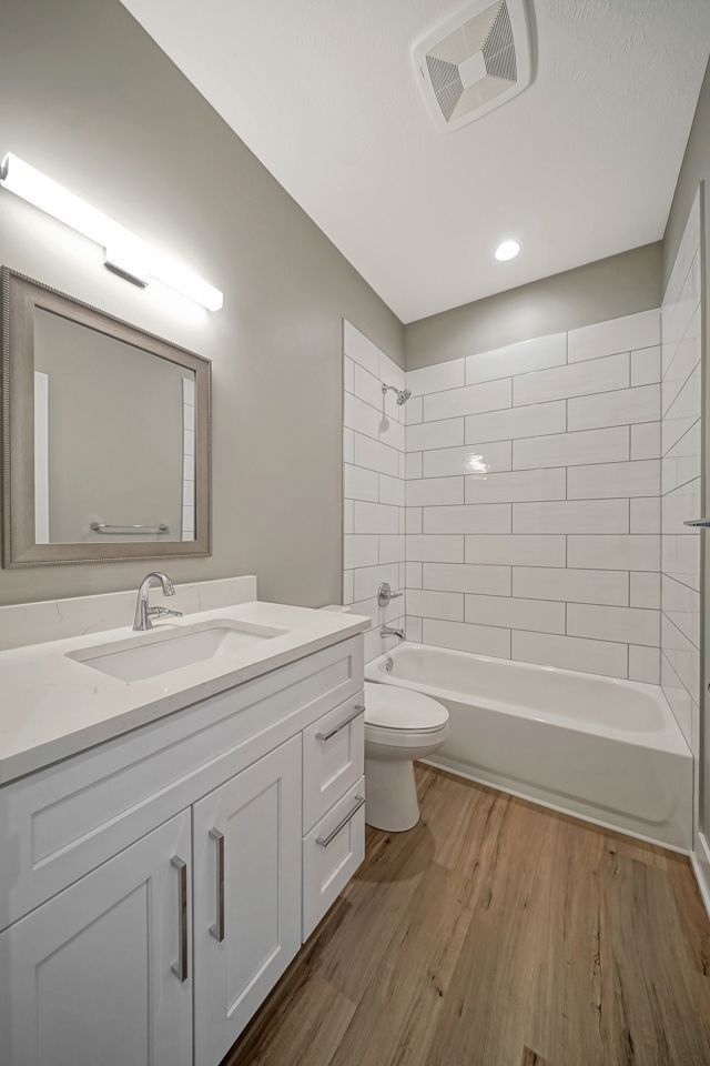 A bathroom with a sink , toilet , tub and mirror.