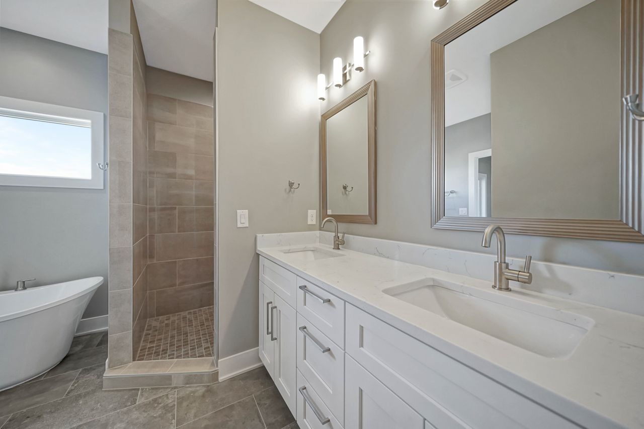 A bathroom with two sinks , a tub and a walk in shower.