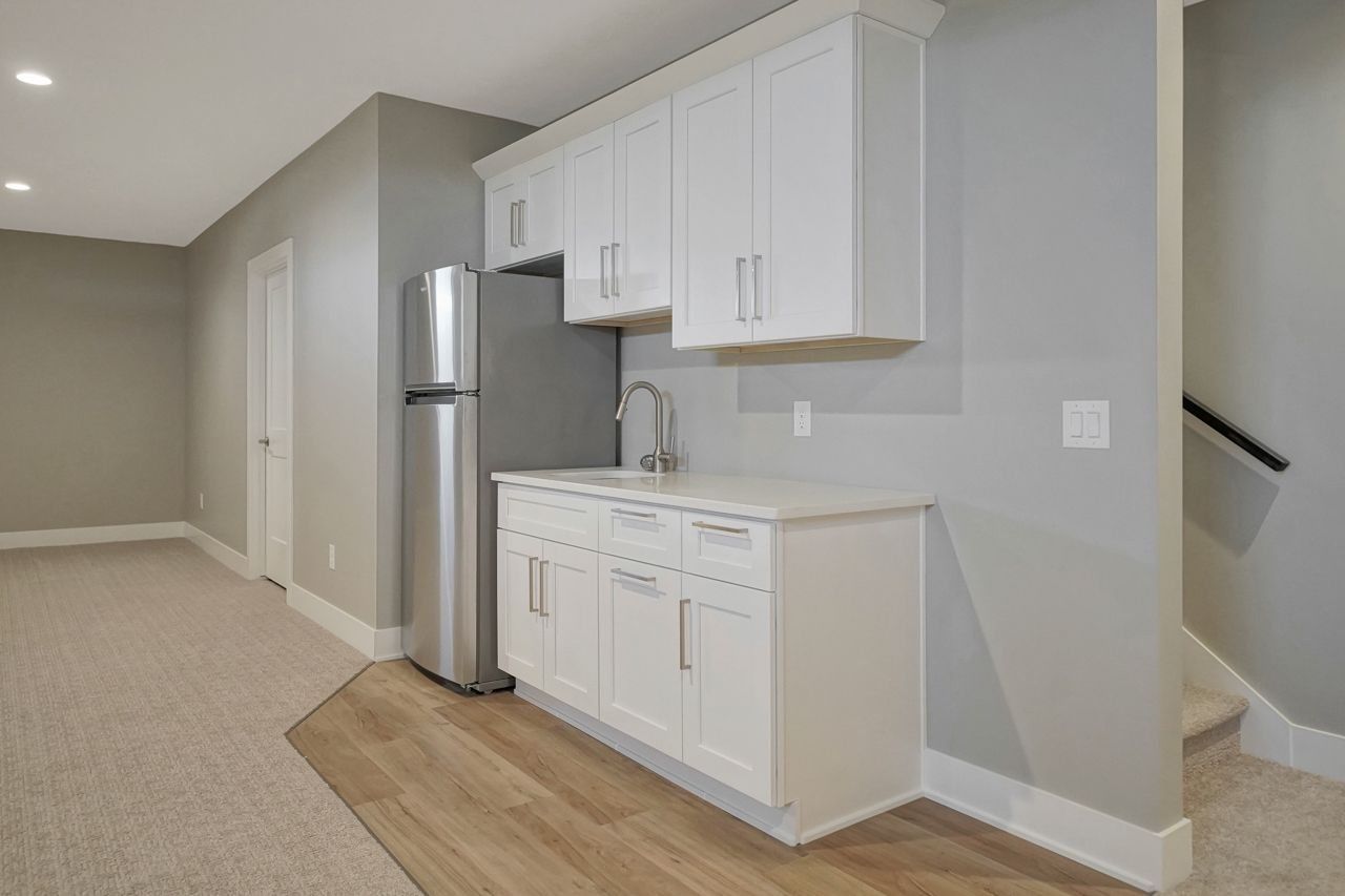A kitchen with white cabinets , a refrigerator and a sink.