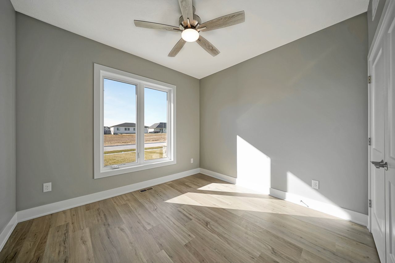 An open stairwell with a wood slat accent wall, pendant lights, lit floating shelves and a walk-in pantry off an empty room with wood-look plank flooring.