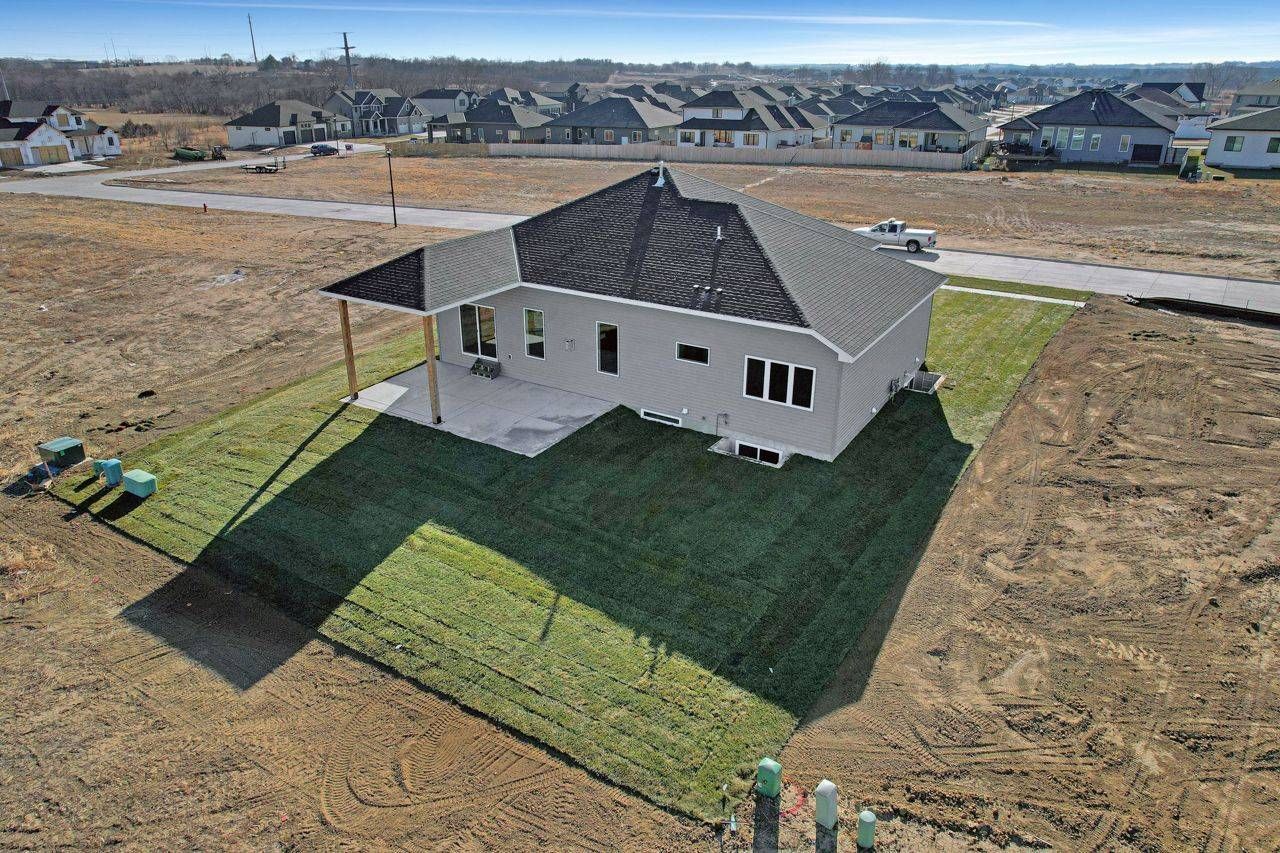 An aerial view of a house sitting on top of a lush green field.