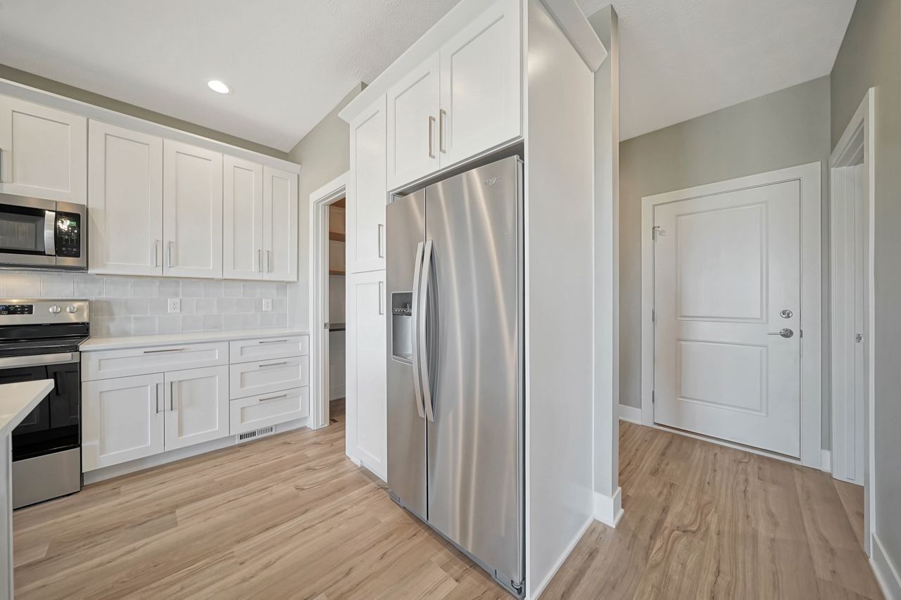 A kitchen with stainless steel appliances and white cabinets.