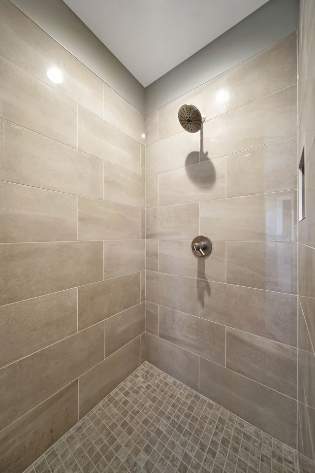 A walk in shower with tiled walls and a tiled floor.