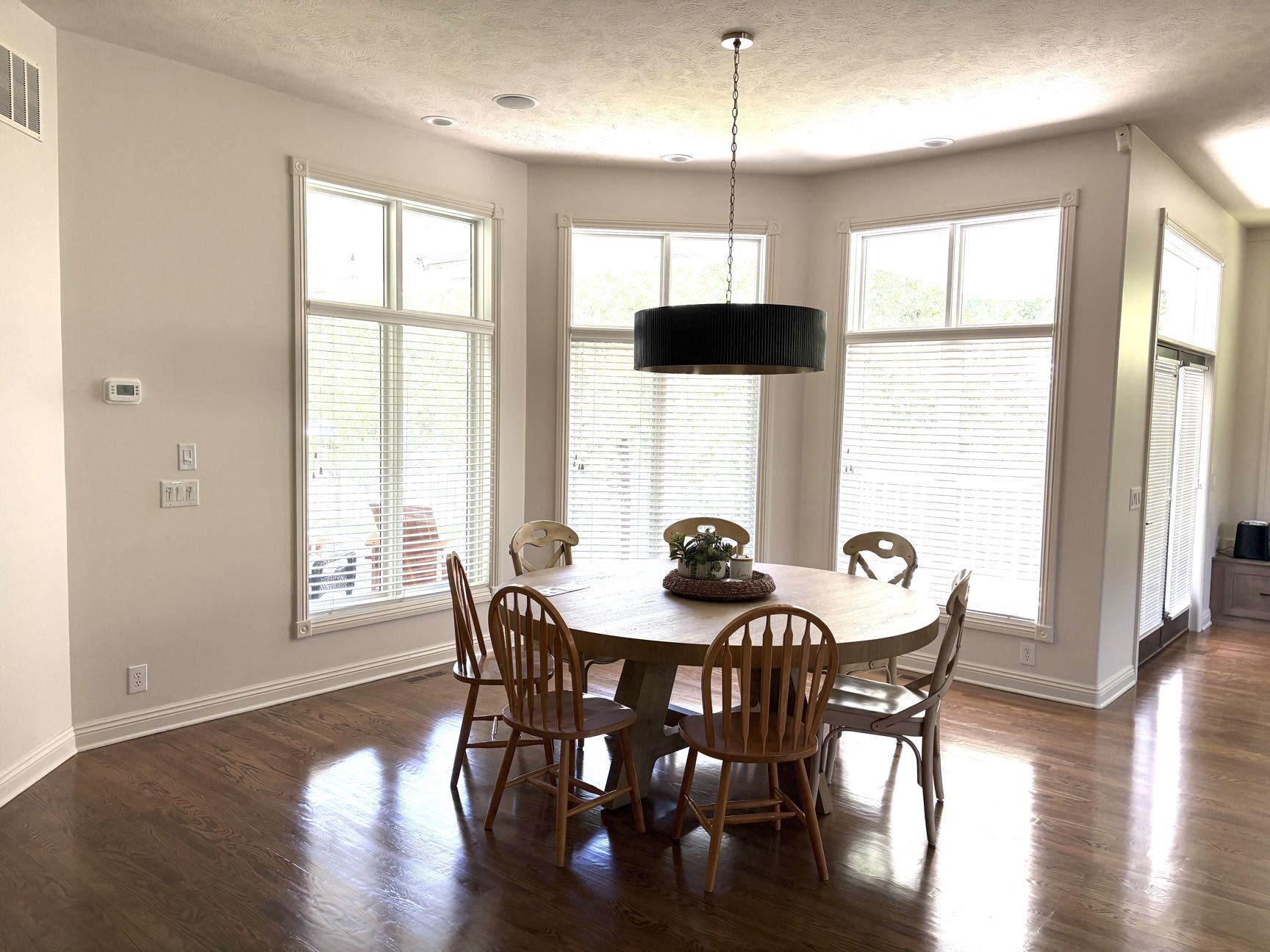 A breakfast nook with a round wood table and chairs beneath a black pendant light in a bay window, Lincoln, NE.