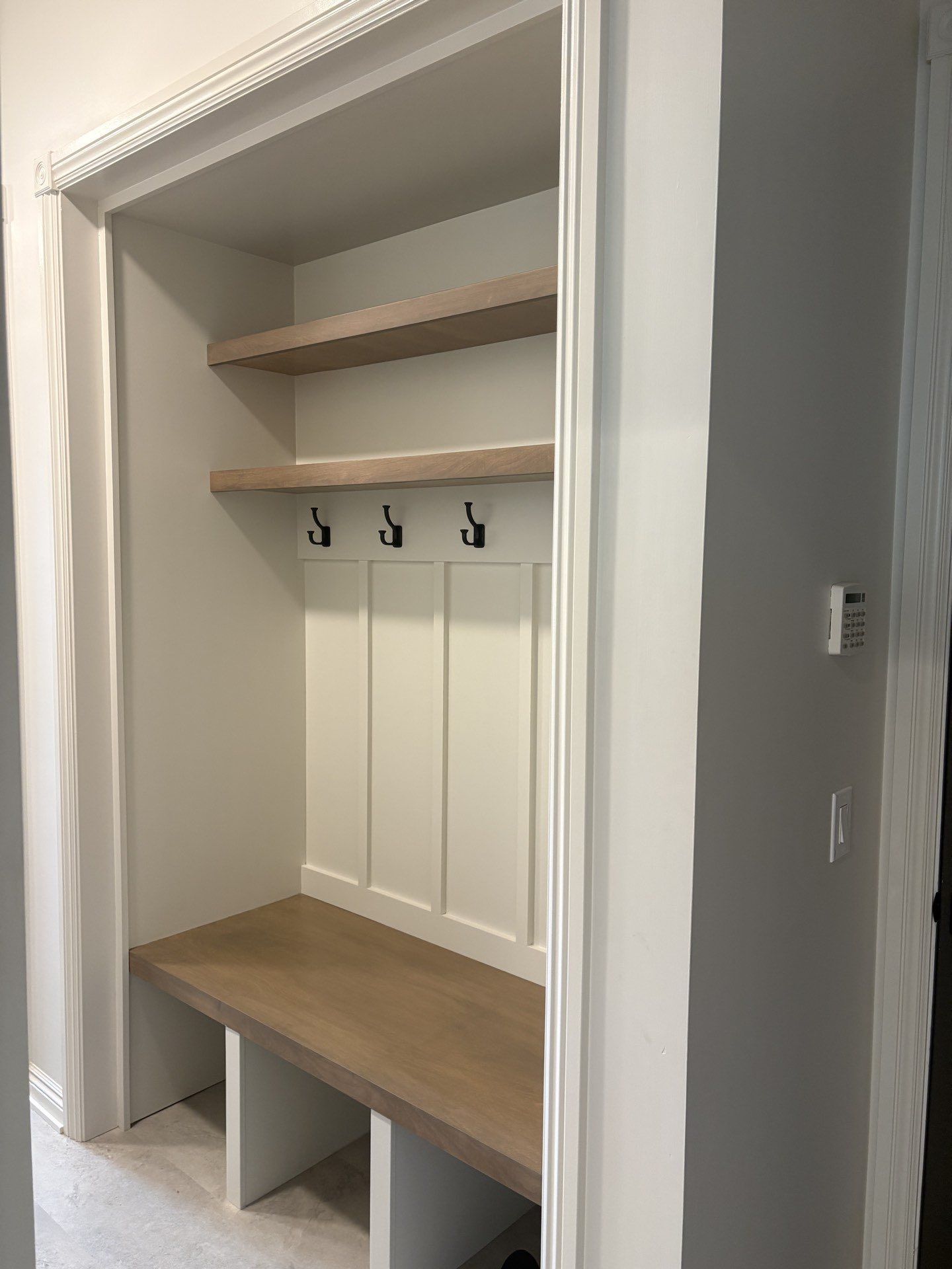 A mudroom with built-in coat hooks, an open shelf and a wood bench, Lincoln, NE.