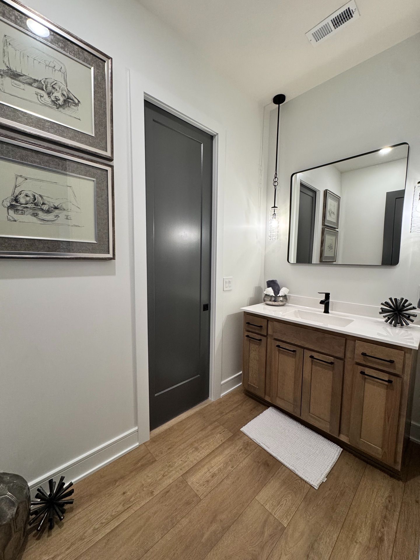 A bathroom with a sink , mirror , and wooden cabinets.
