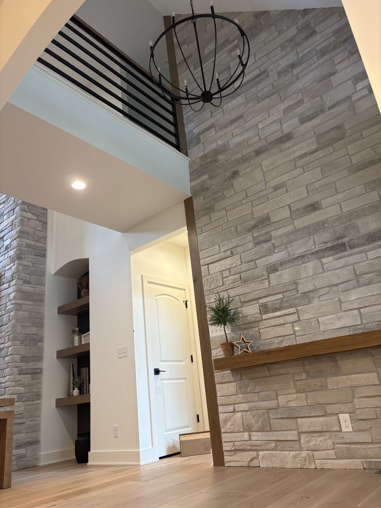 An entry hall with a stacked-stone accent wall and a black pendant chandelier, Lincoln, NE.
