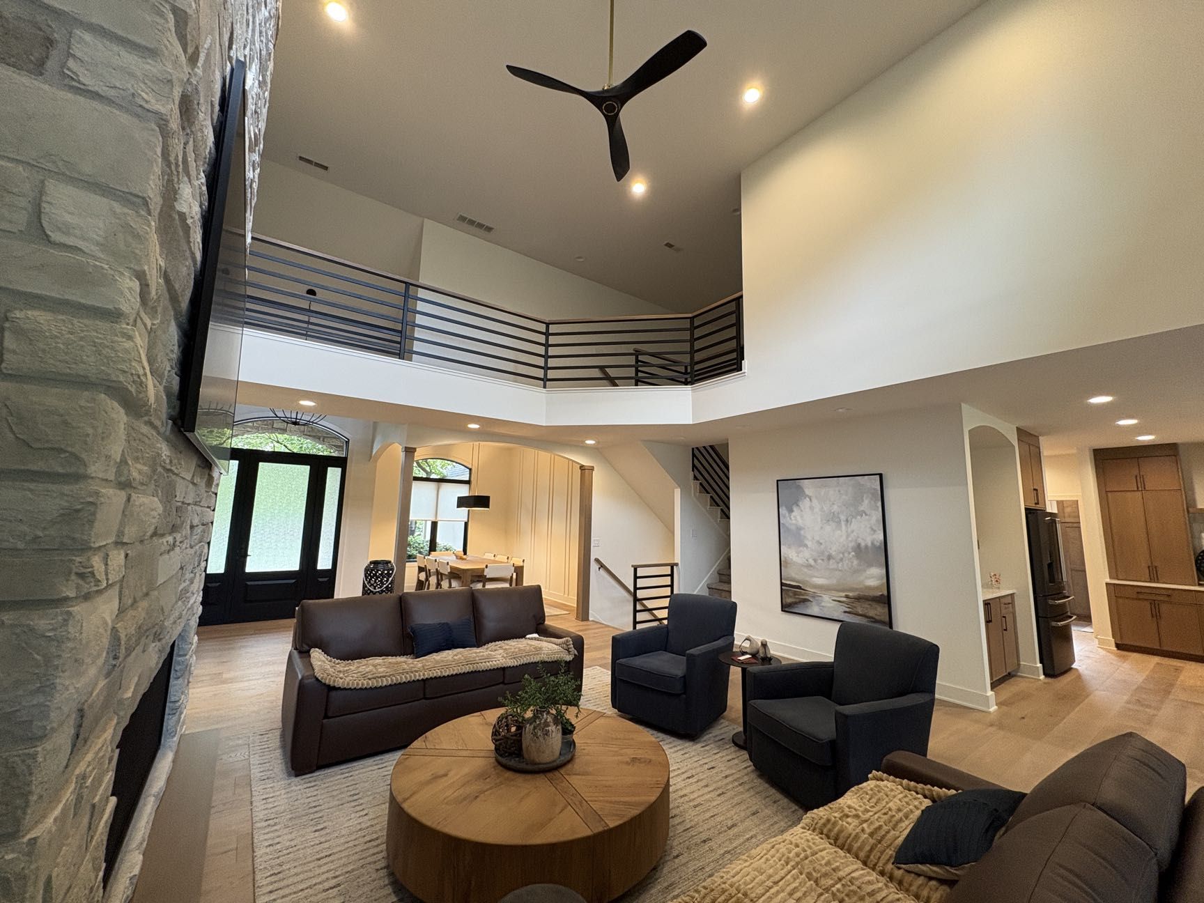 A living room with leather seating, a round coffee table, and a two-story loft overlook, Lincoln, NE.