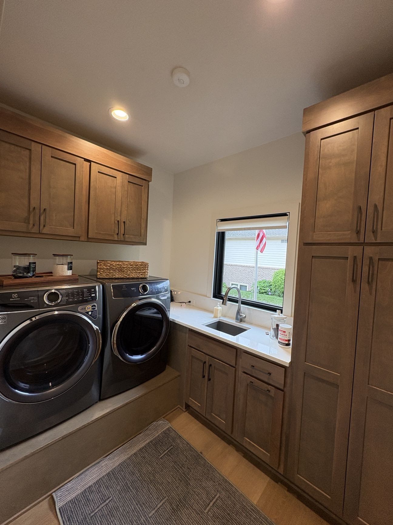 A laundry room with stained wood cabinetry, quartz counters, and a front-load washer and dryer, Lincoln, NE.