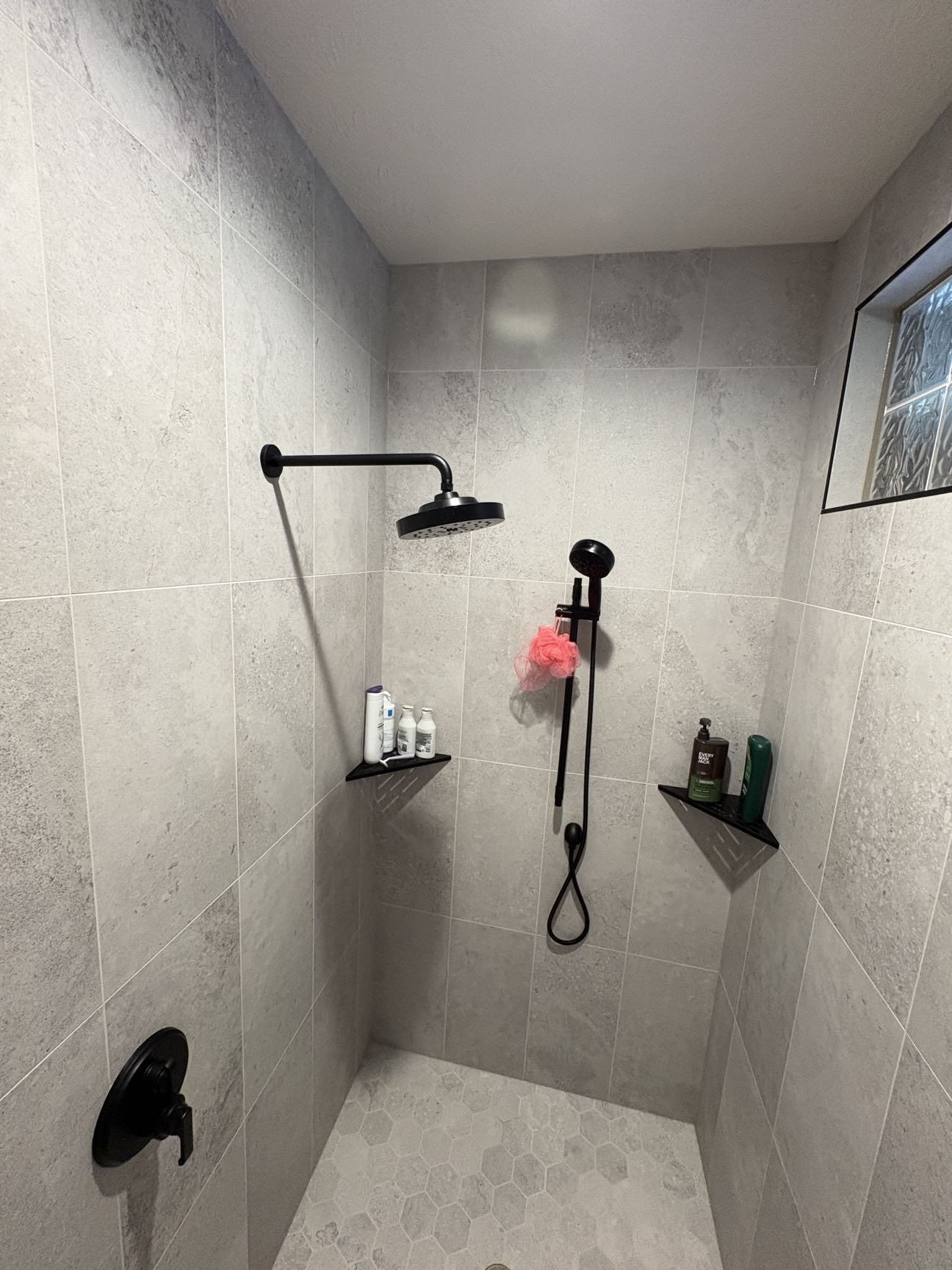 A primary bathroom walk-in shower with tile surround, a glass-block window, and black fixtures, Lincoln, NE.
