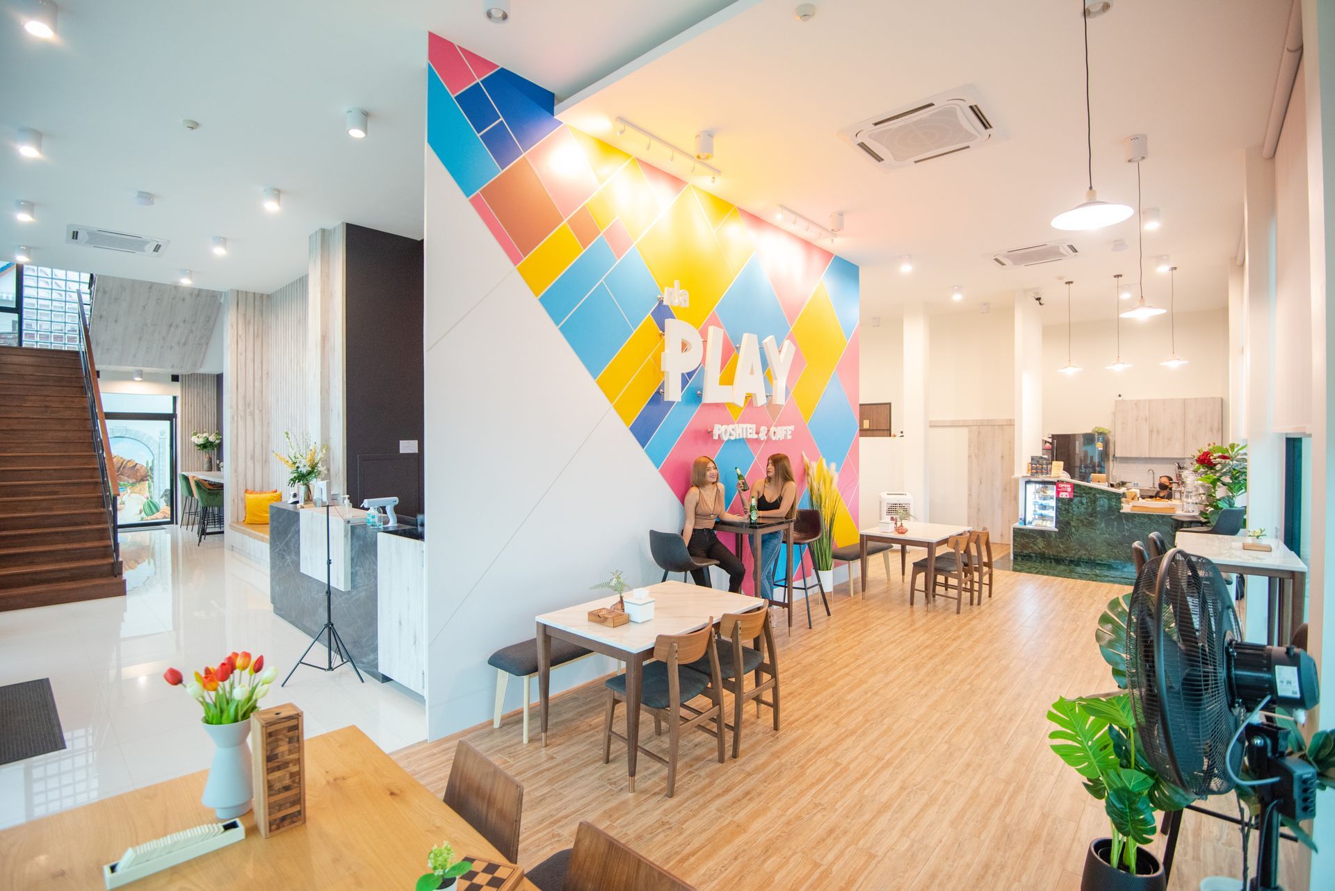 Colorful cafe interior with customers. Large wall art reads