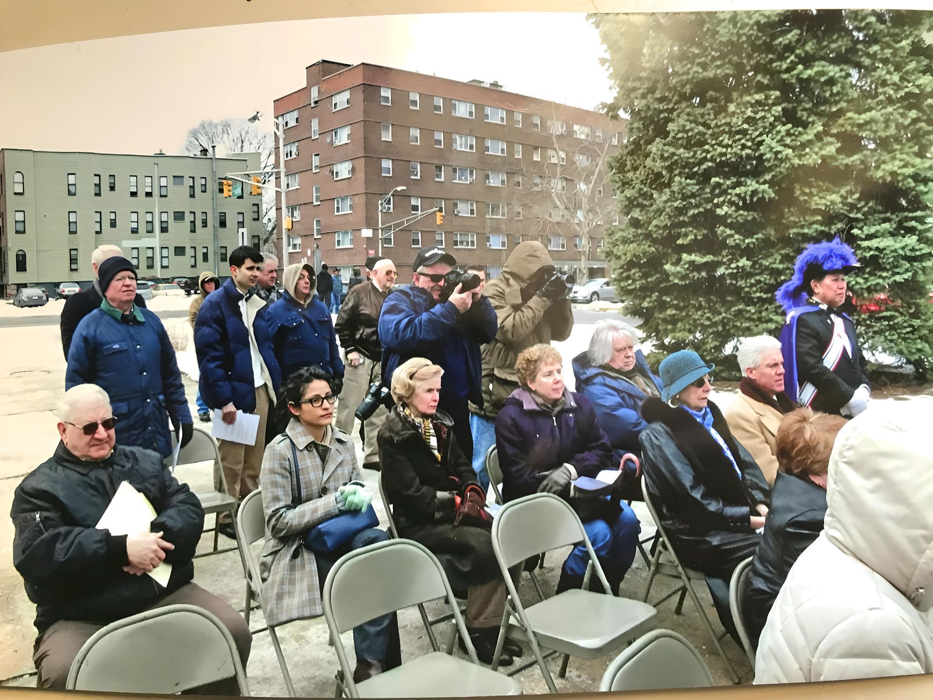 A group of people sitting in folding chairs in front of a building