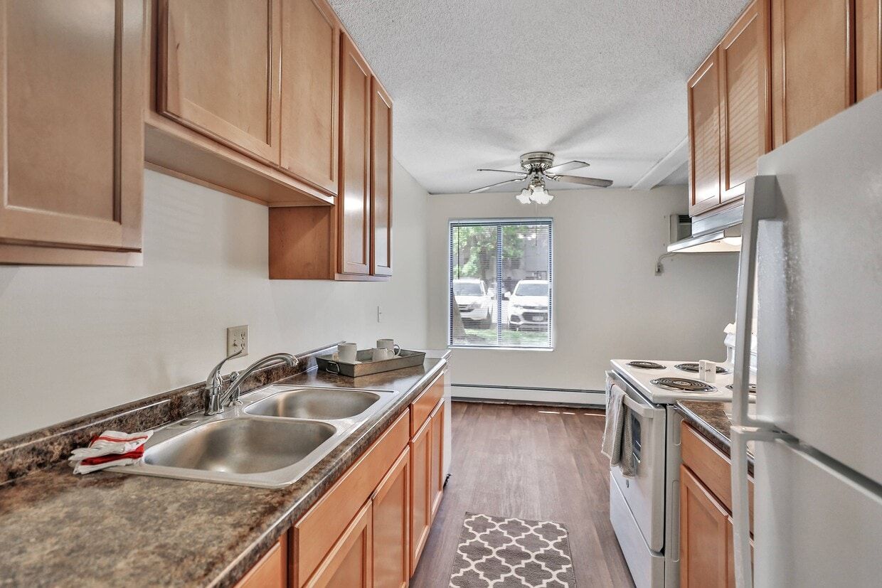 Kitchen with brown cabinets, a double sink, white appliances, and a window with a view outside.