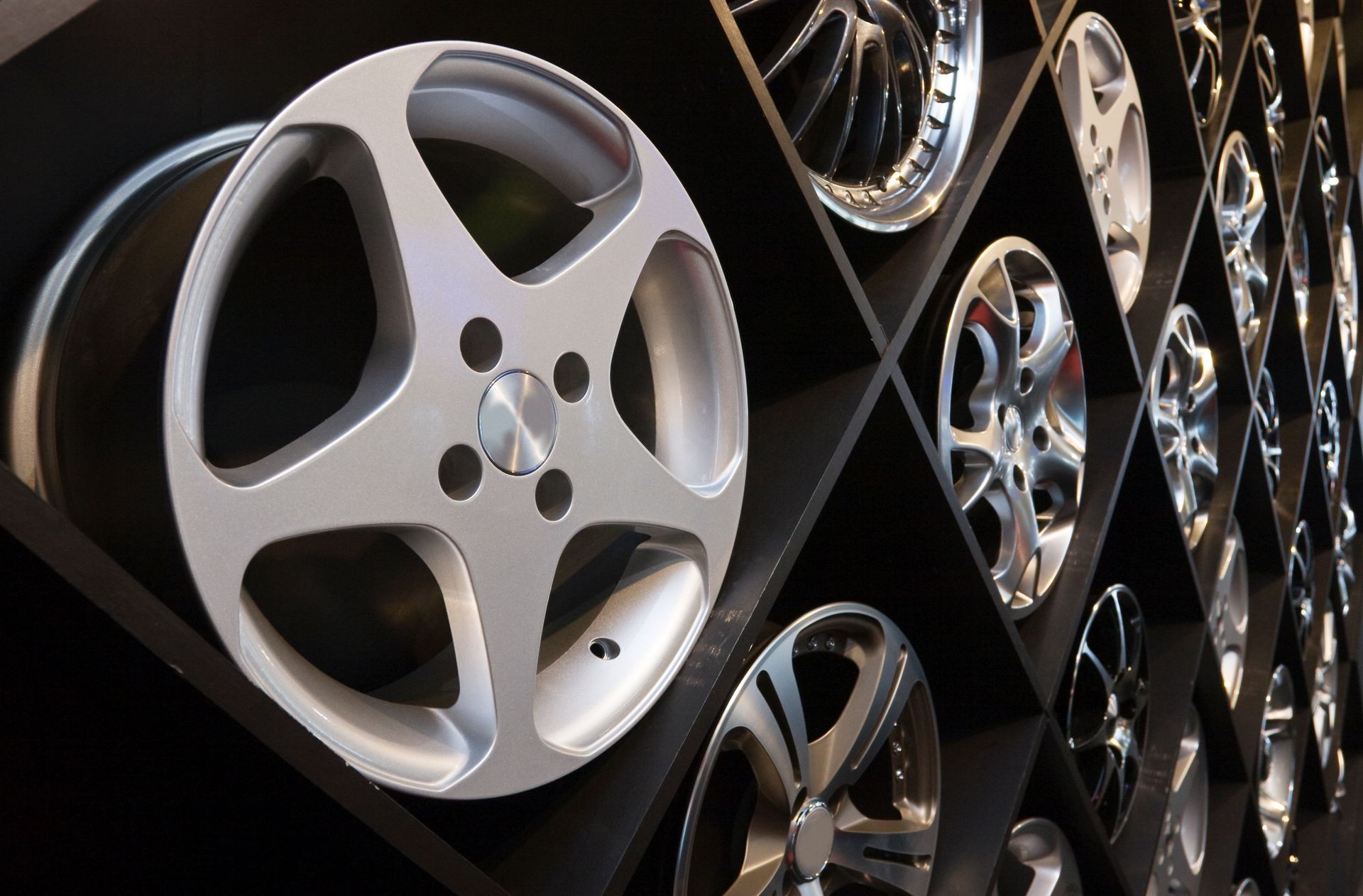 A row of silver wheels on a black shelf
