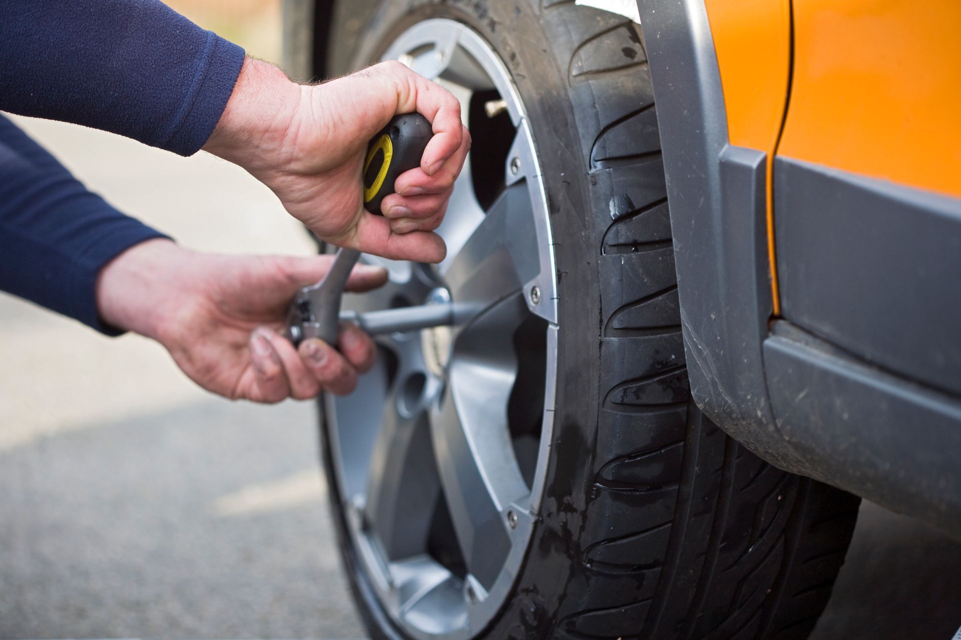 A man is pumping air into a tire on a car.