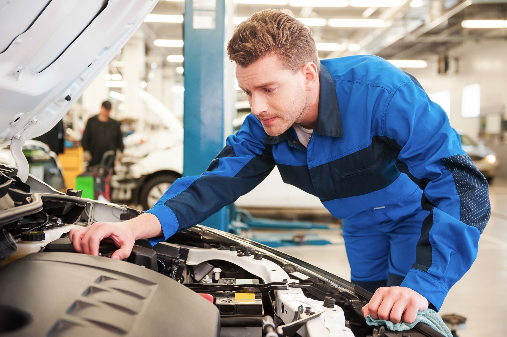 A man is working on the engine of a car in a garage.
