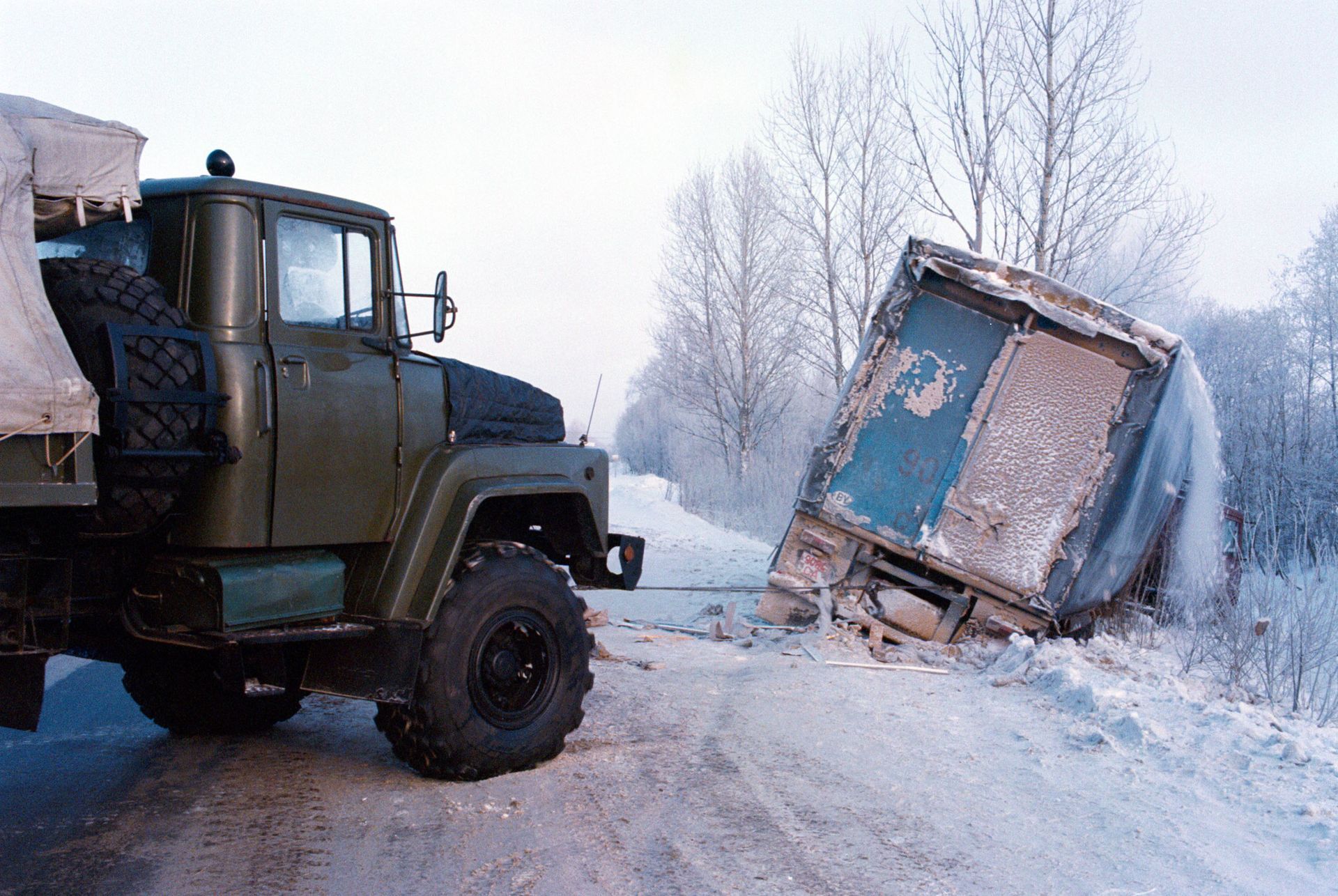 A truck is towing a trailer that has fallen off the road.