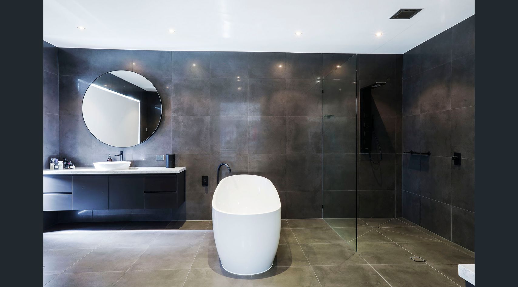 A tiled walk-in shower with a glass door, pebble floor, white subway tile walls, and a towel rack on the exterior wall.