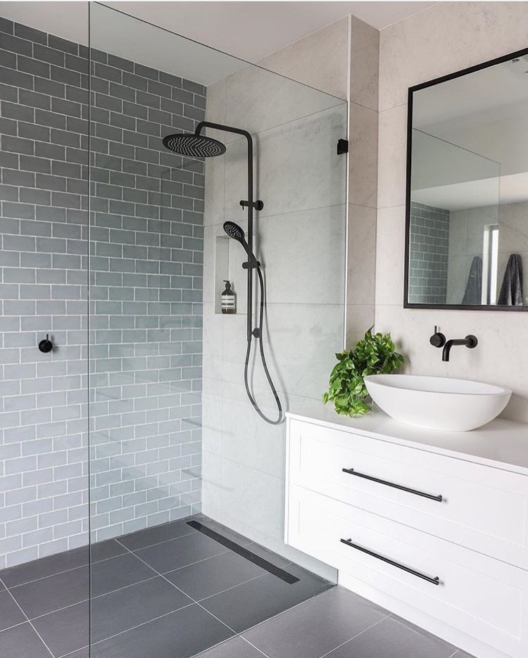 Modern bathroom with white marble-patterned walls, a glass shower stall, a wood vanity, and a wall-mounted toilet.