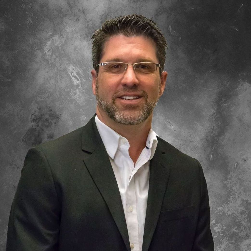 A man in a suit and glasses is smiling for the camera.
