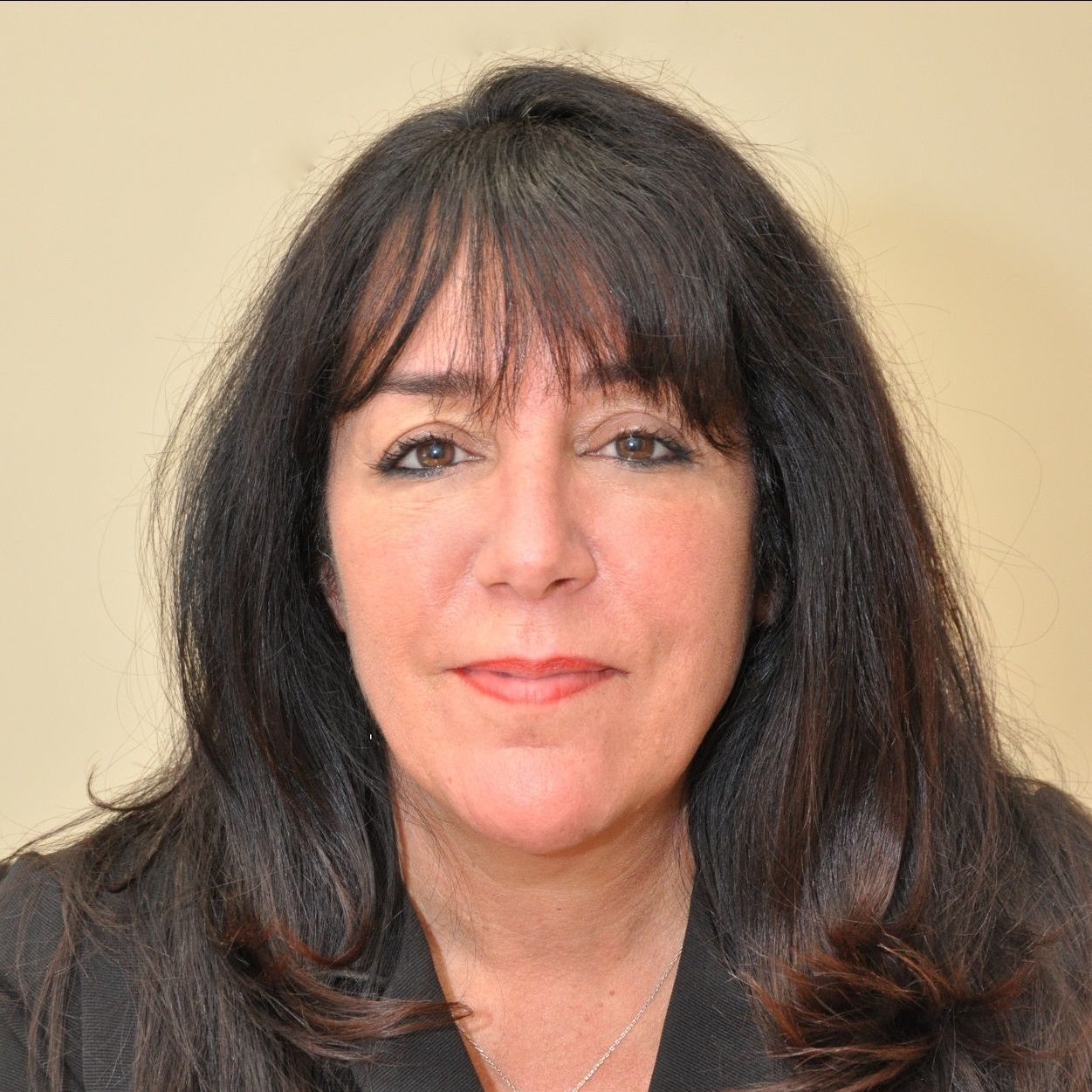 A woman with long black hair and bangs is smiling for the camera.