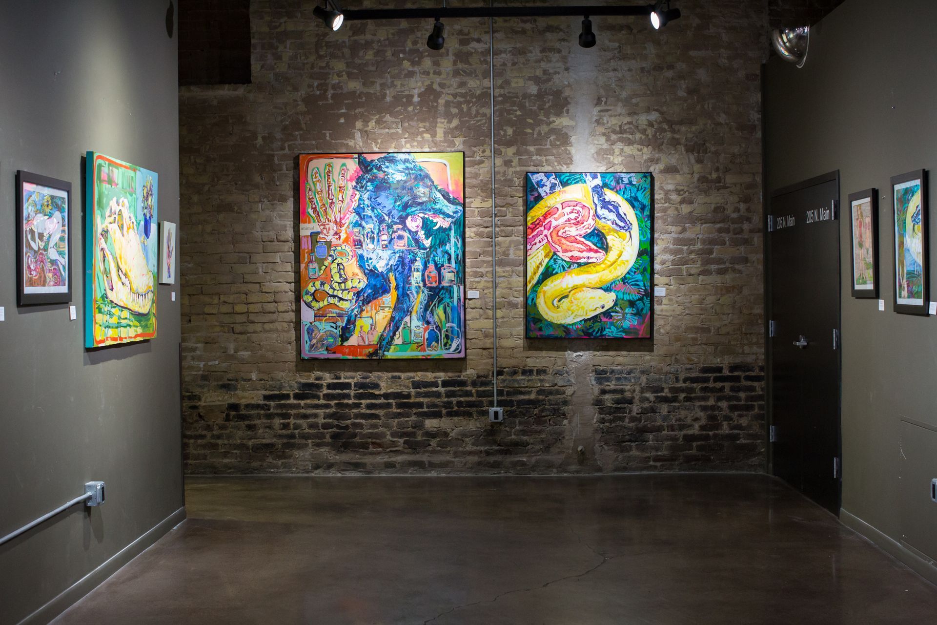 a room with a brick wall and paintings on the wall .