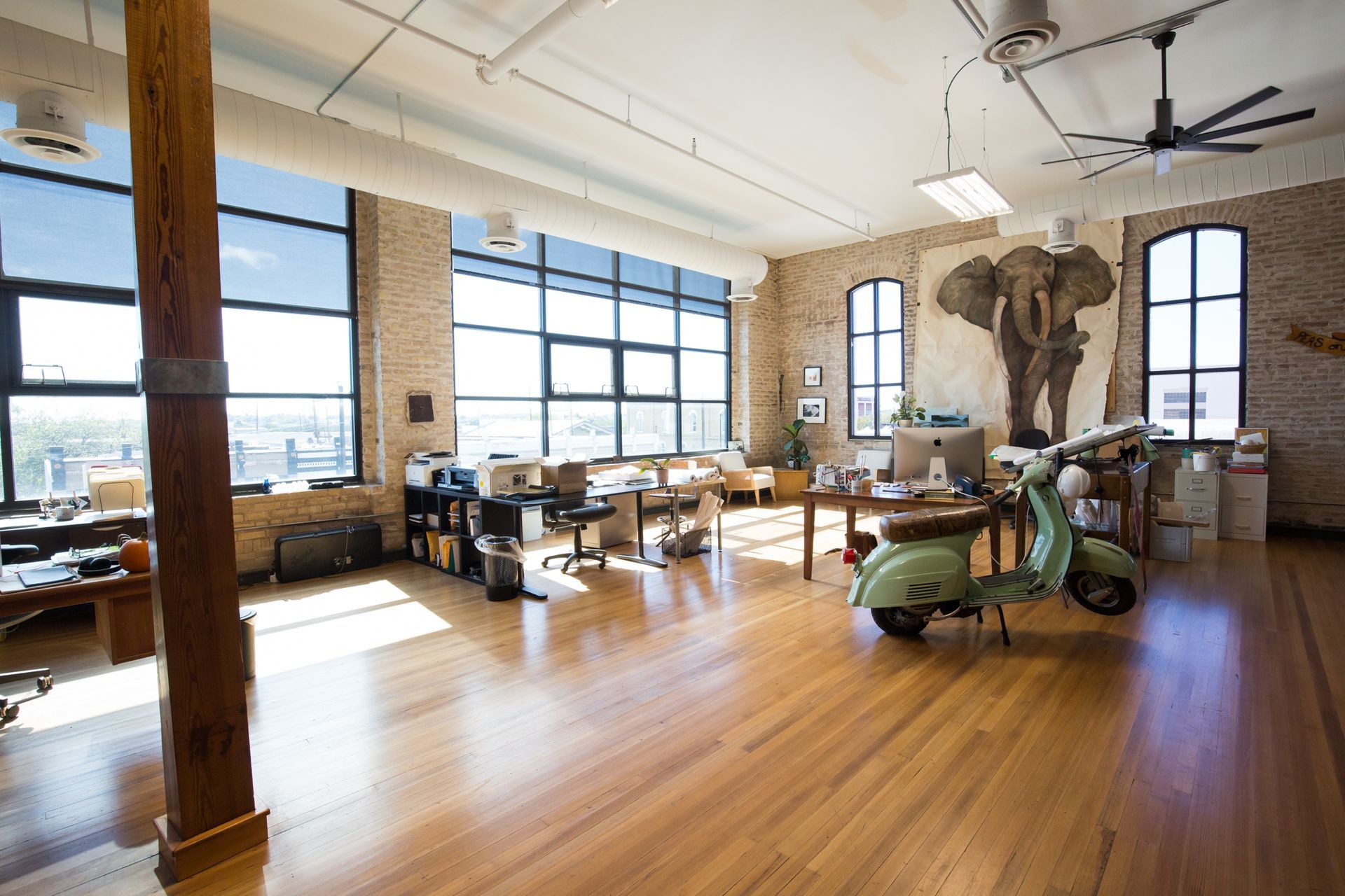 a green scooter is parked in a large room with a statue of an elephant on the wall .