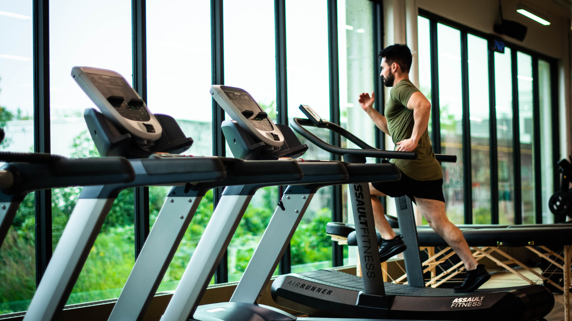 A man is running on a treadmill in a gym.