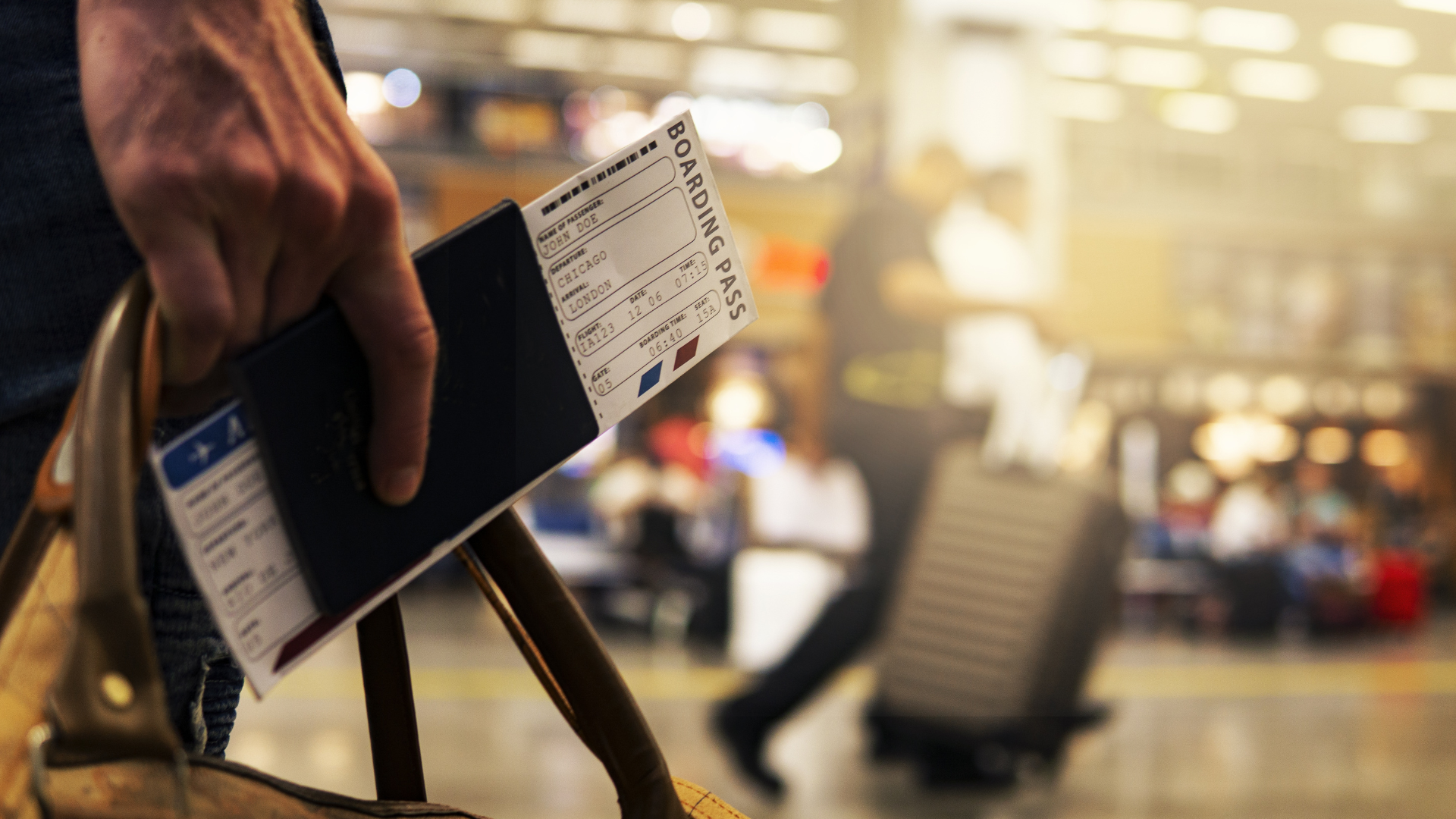 A person is holding a passport and a ticket at an airport.