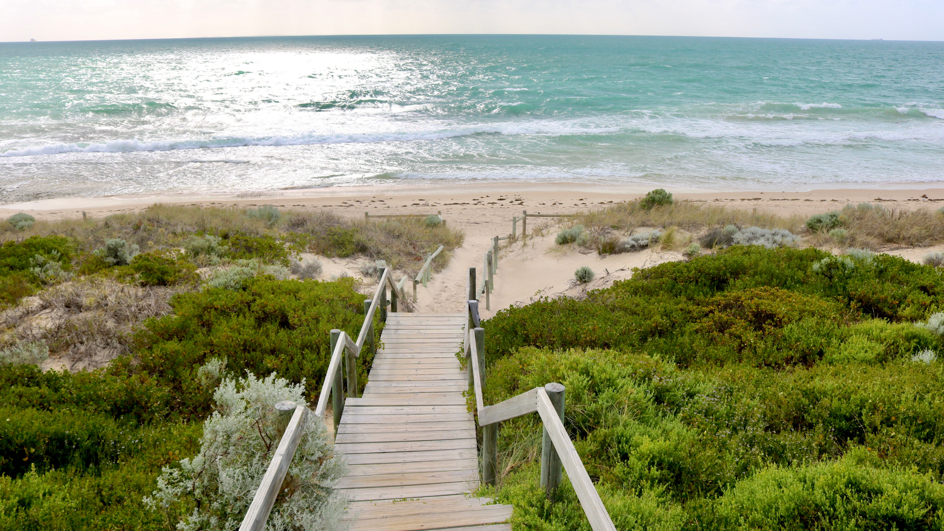 There is a wooden walkway leading to the beach.