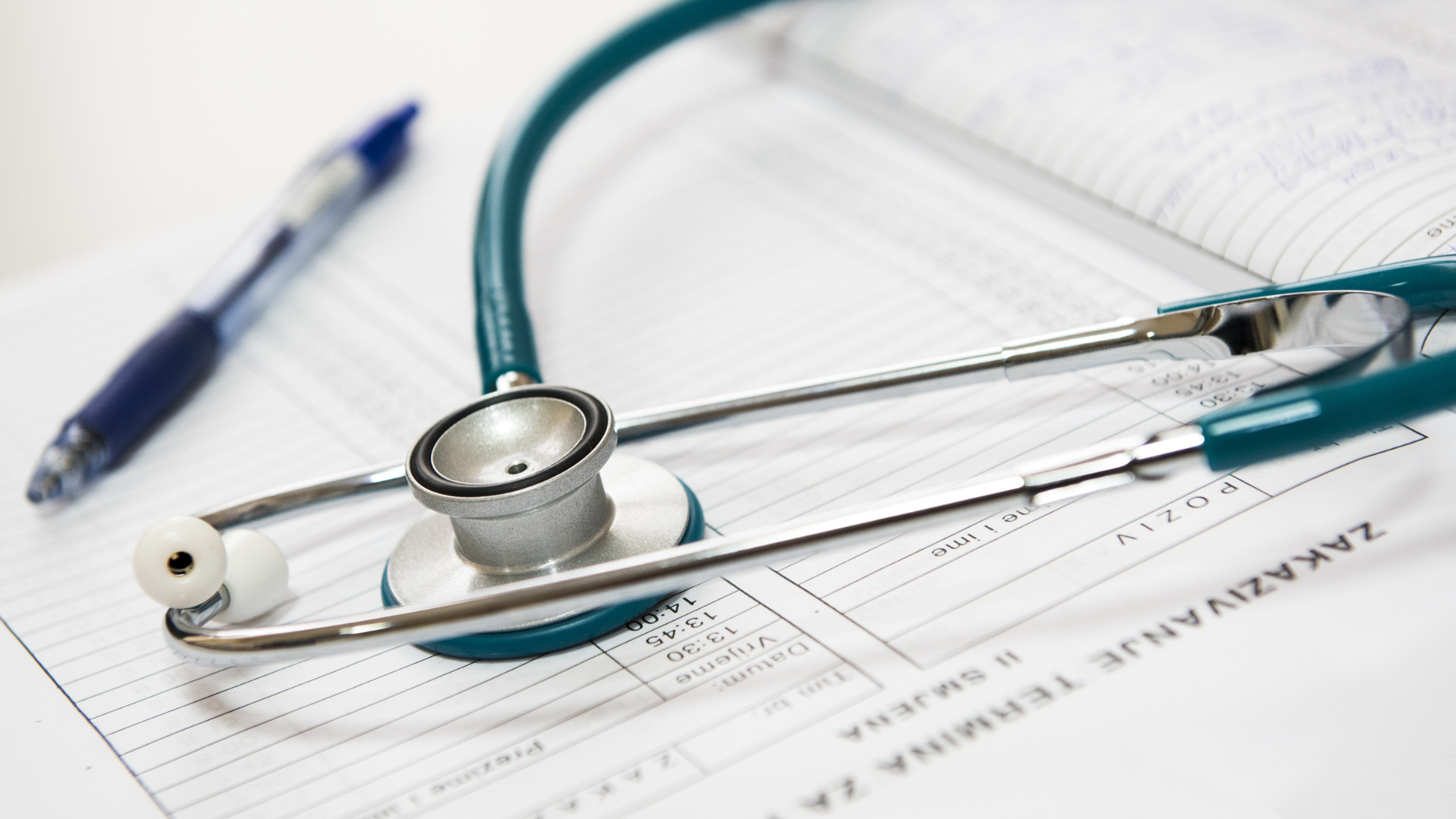 A stethoscope is sitting on top of a piece of paper next to a pen.