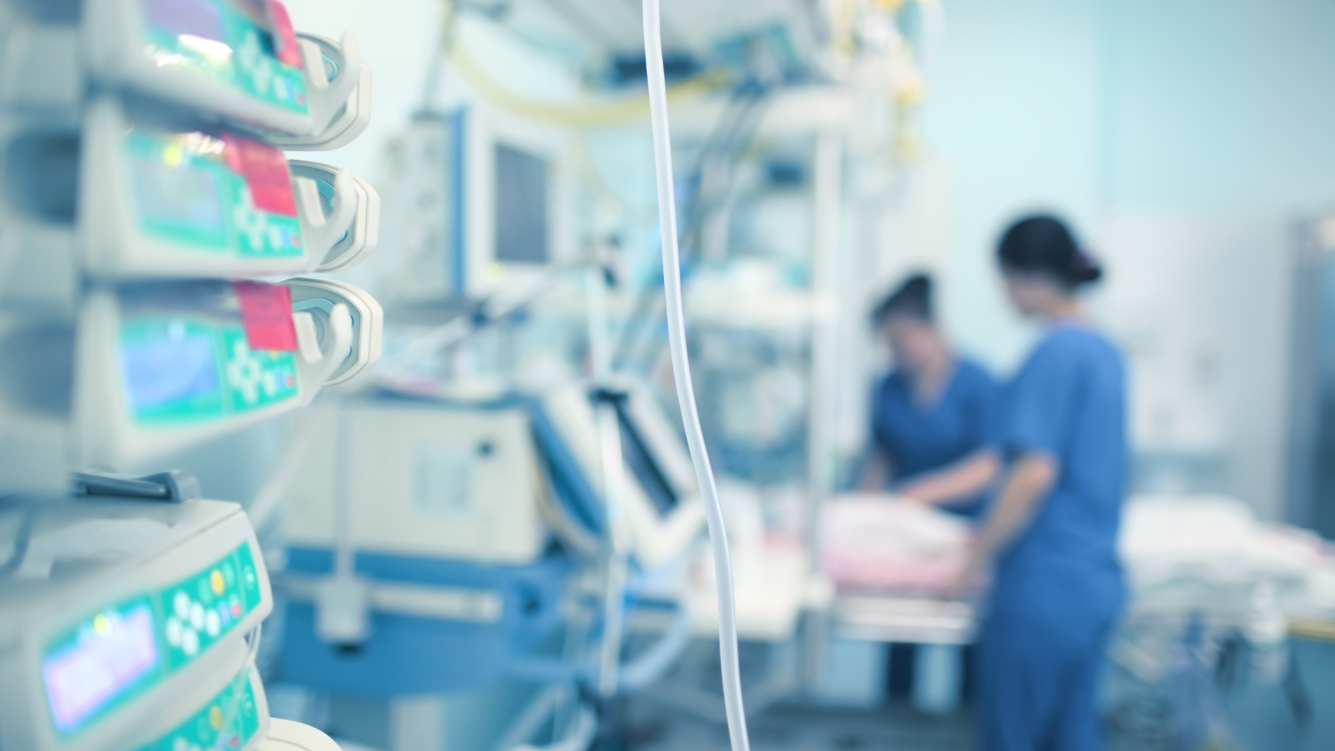 A blurry picture of a hospital room with nurses and a patient in a hospital bed.
