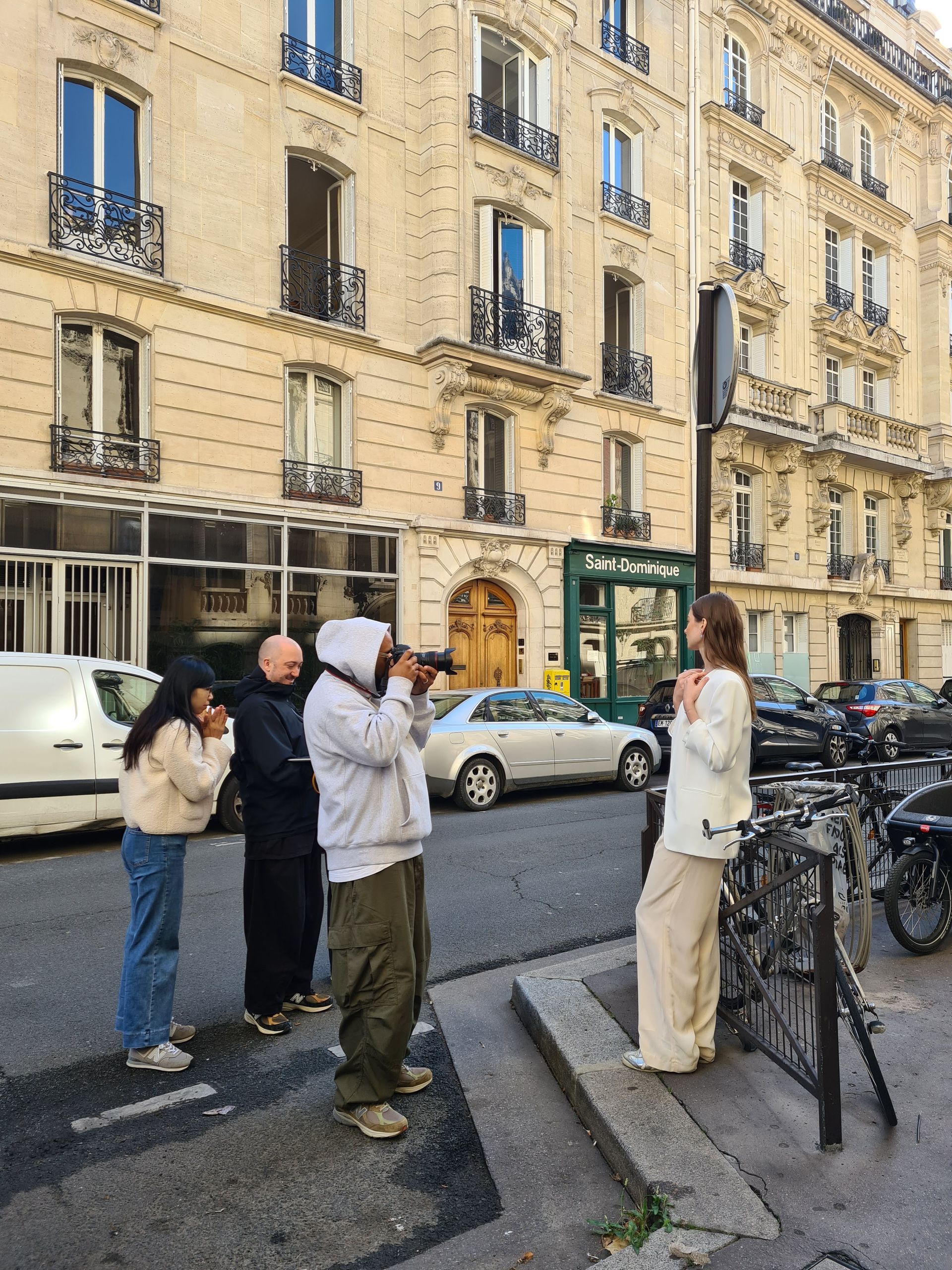 攝影師正在拍攝一位在歐式建築前的人行道上擺姿勢的女士。