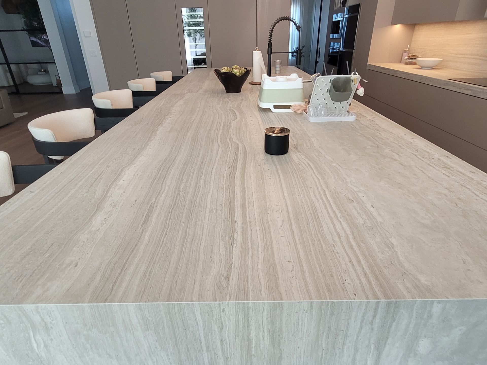 Modern office conference room with a long wood table, white stools, and wall shelves with decor