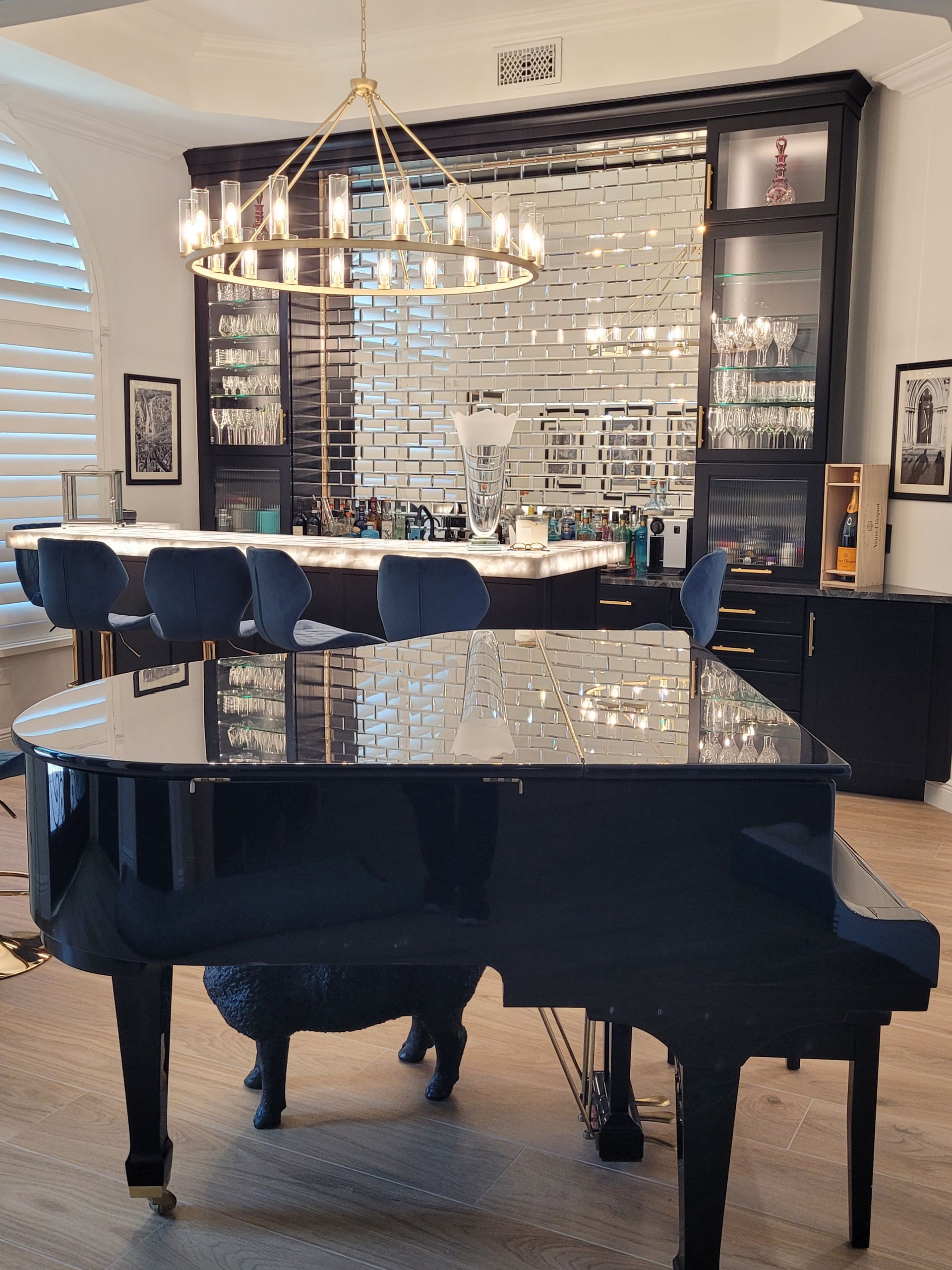 Grand piano in an elegant home bar or music room with mirrored cabinetry and a chandelier overhead