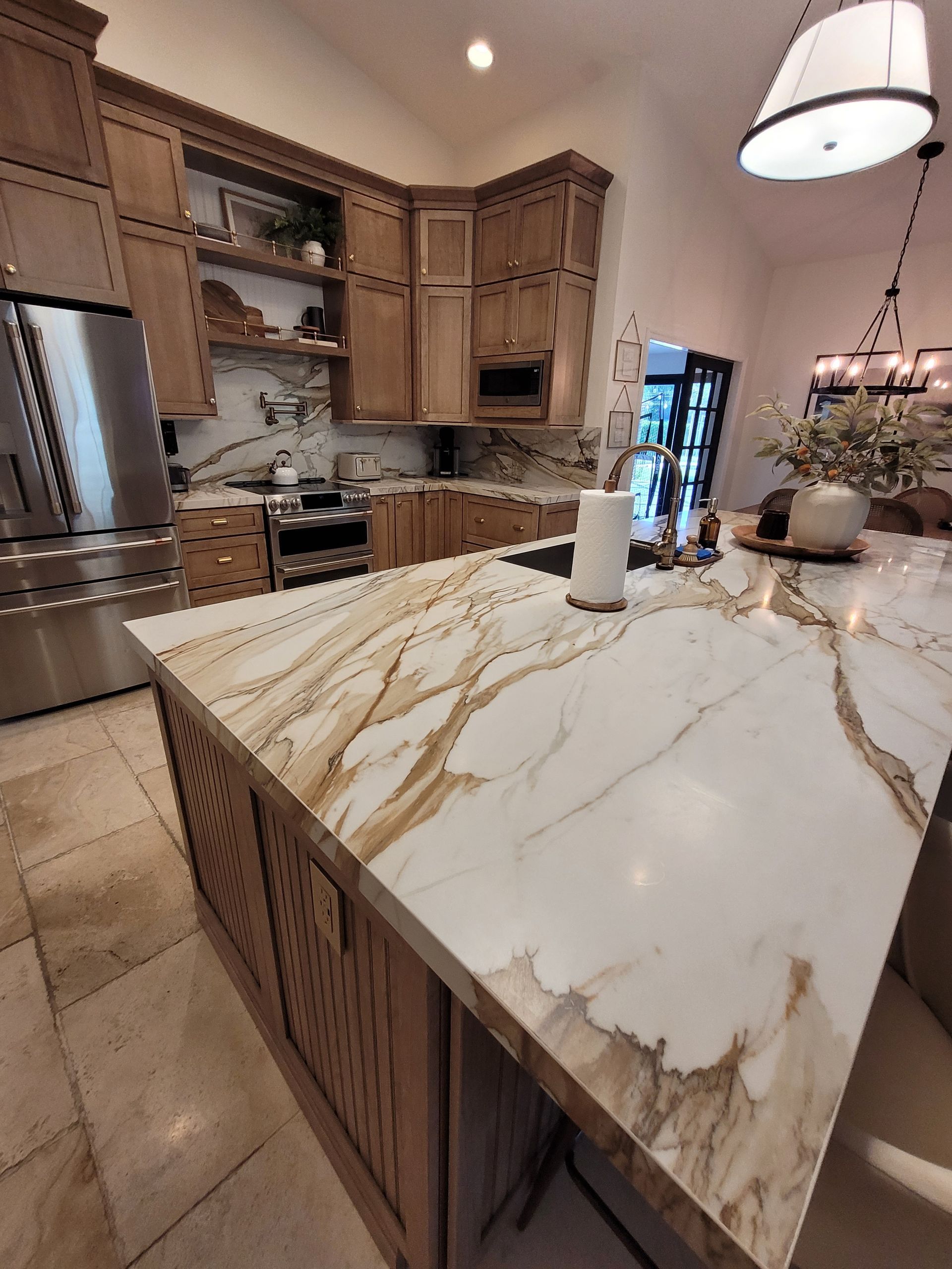 Luxury kitchen with marble island, wood cabinets, and pendant lights