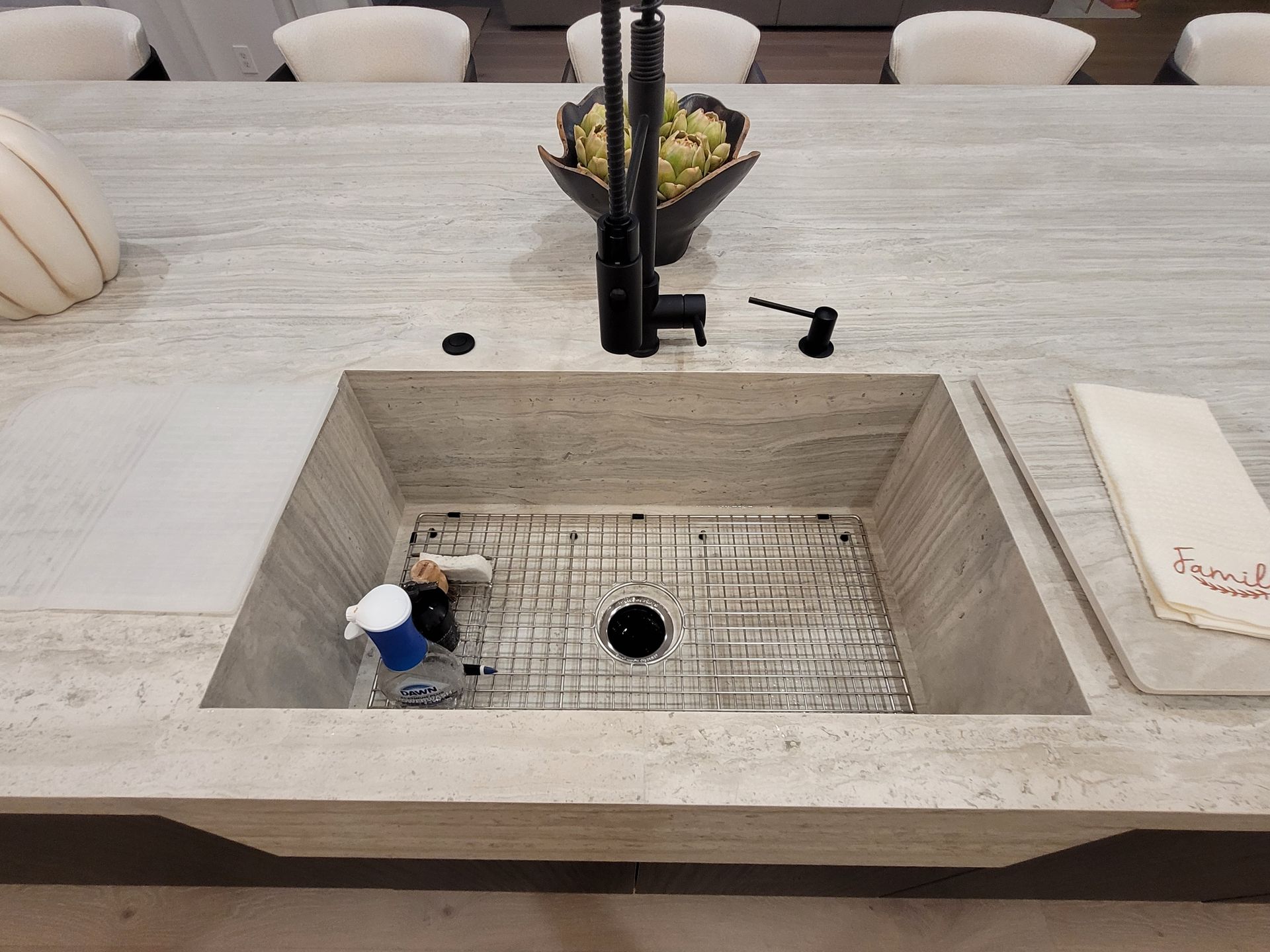 Modern rectangular stone sink with black faucet on a light countertop in a dining area
