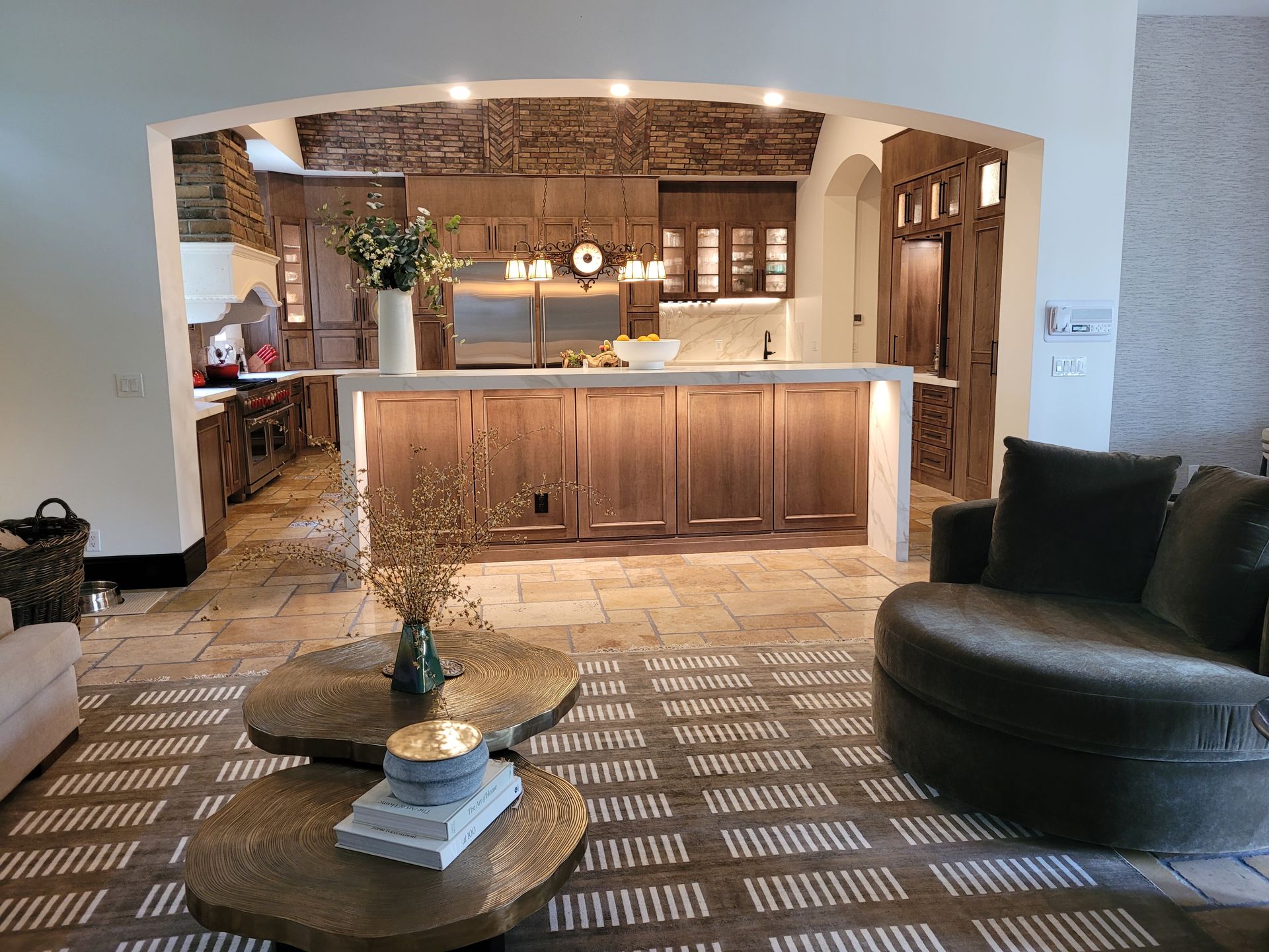 Modern kitchen and lounge with wood cabinets, arched pass-through, and patterned rug