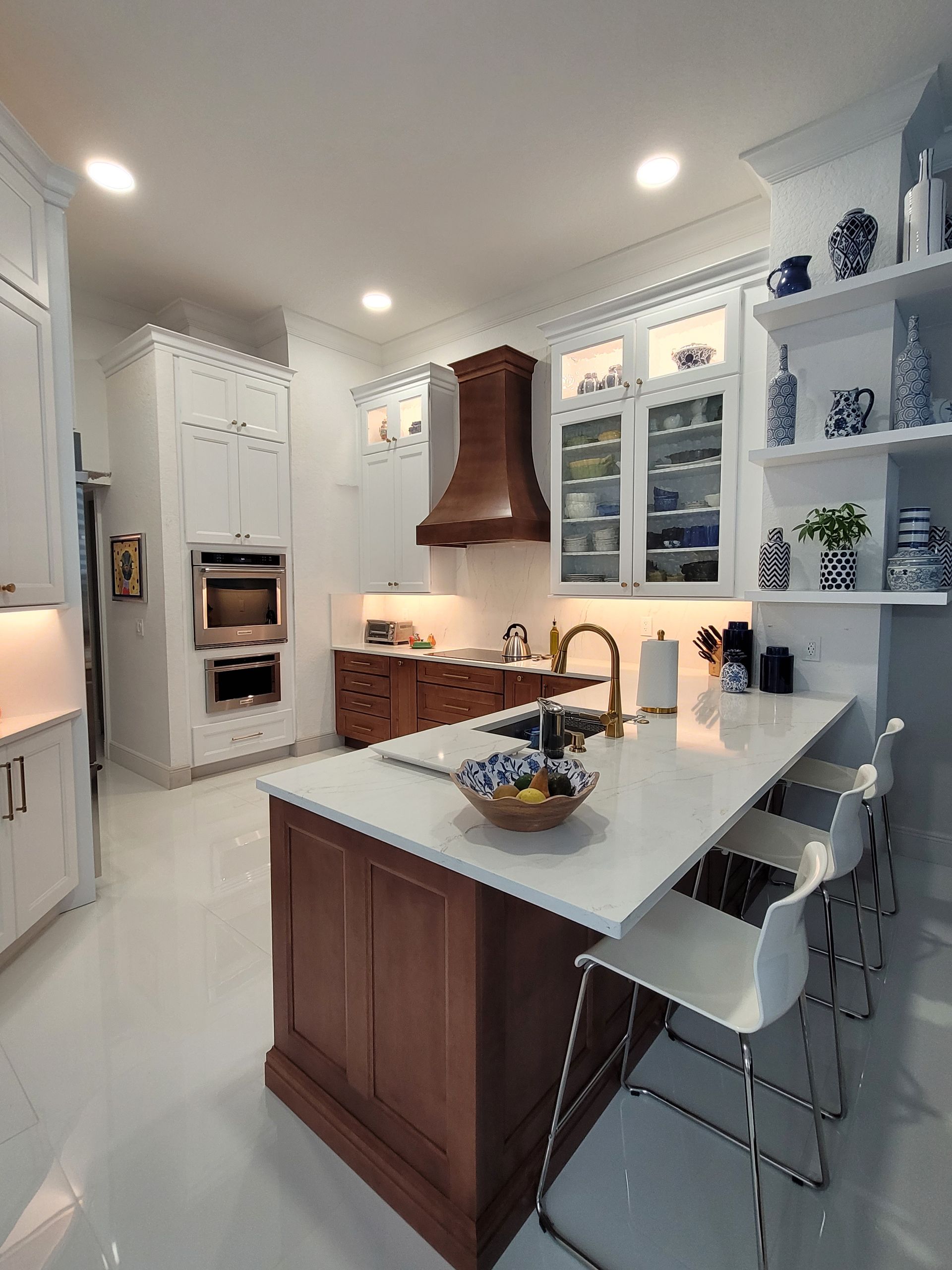 Bright modern white kitchen with wood island, pendant lights, open shelves, and bar stools